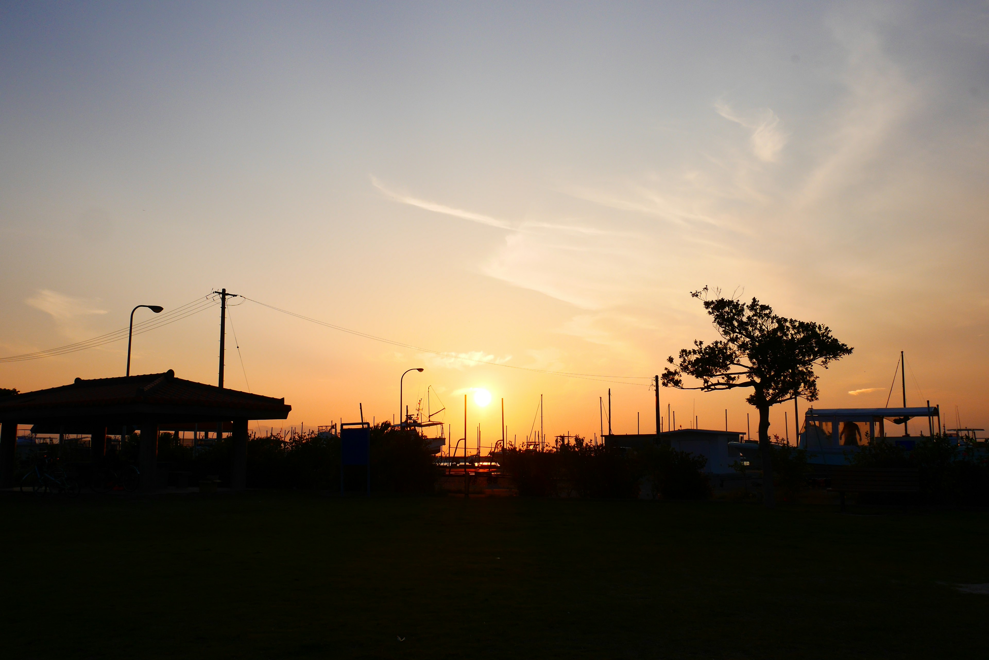 夕日が沈む時間の静かな風景 船と木がシルエットになっている