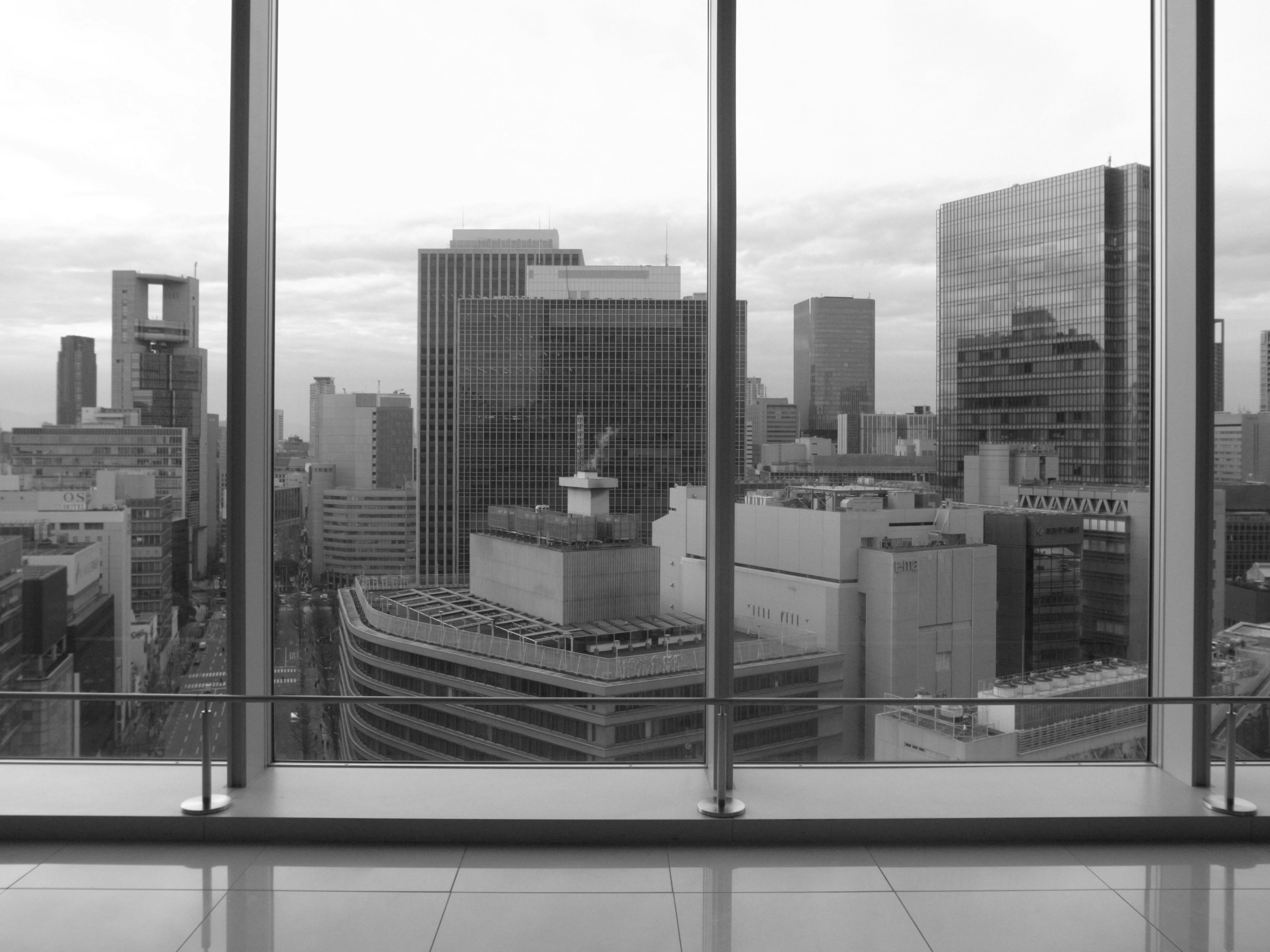 Black and white photo of a cityscape viewed through large glass windows