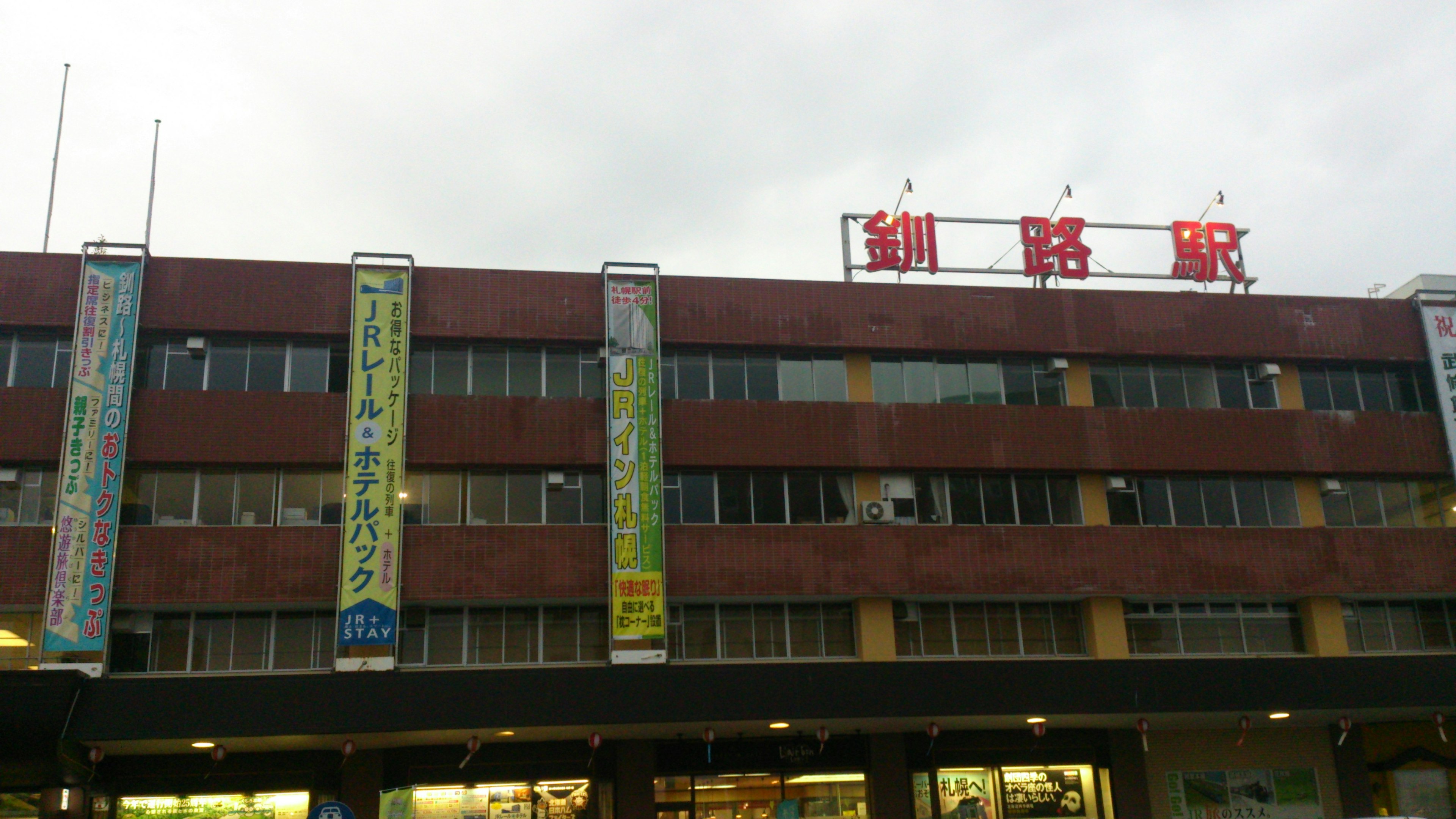 赤い外壁の建物に表示された駅名の看板と広告