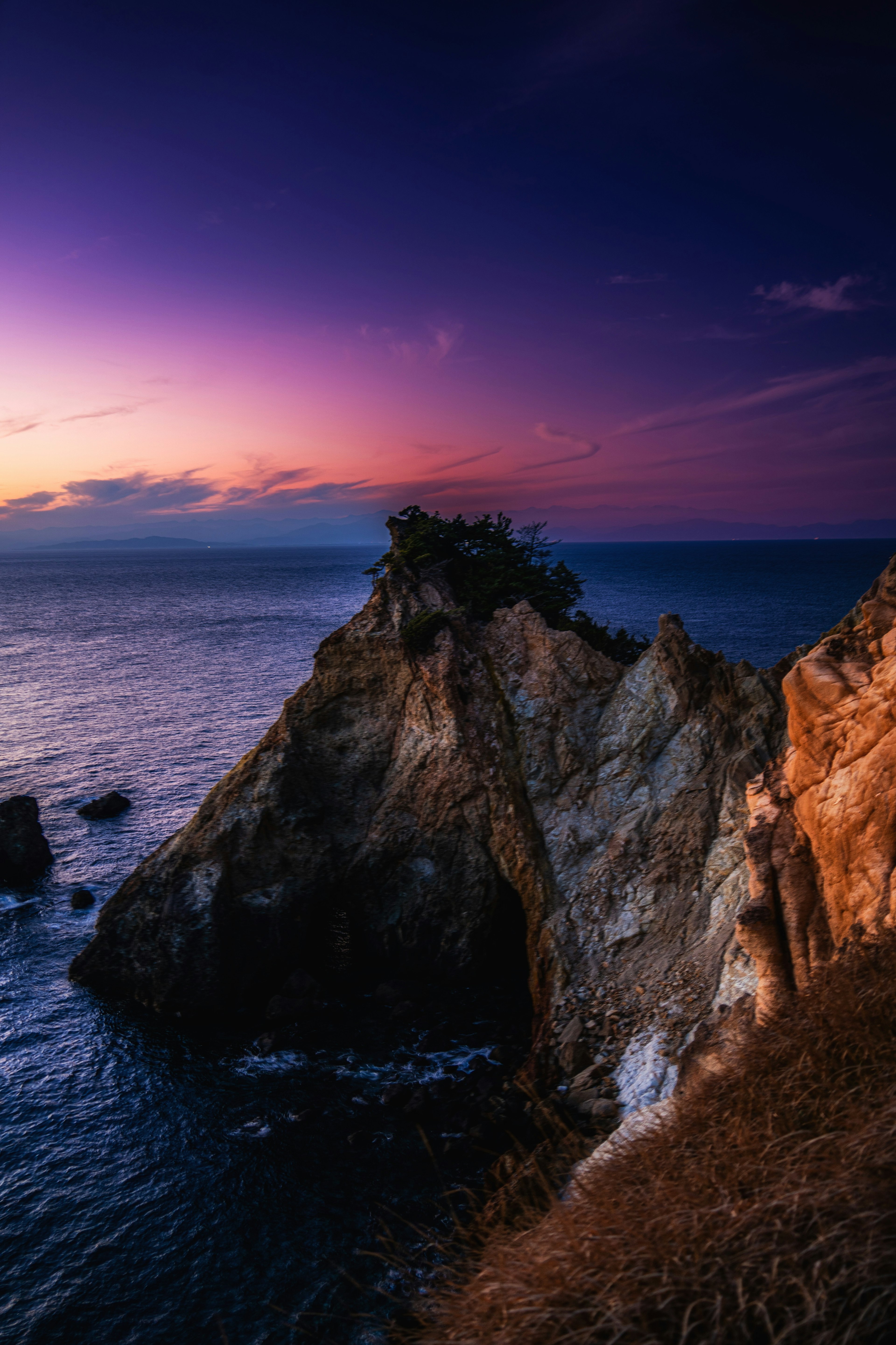 Stunning rocky coastline silhouetted against a vibrant sunset sky