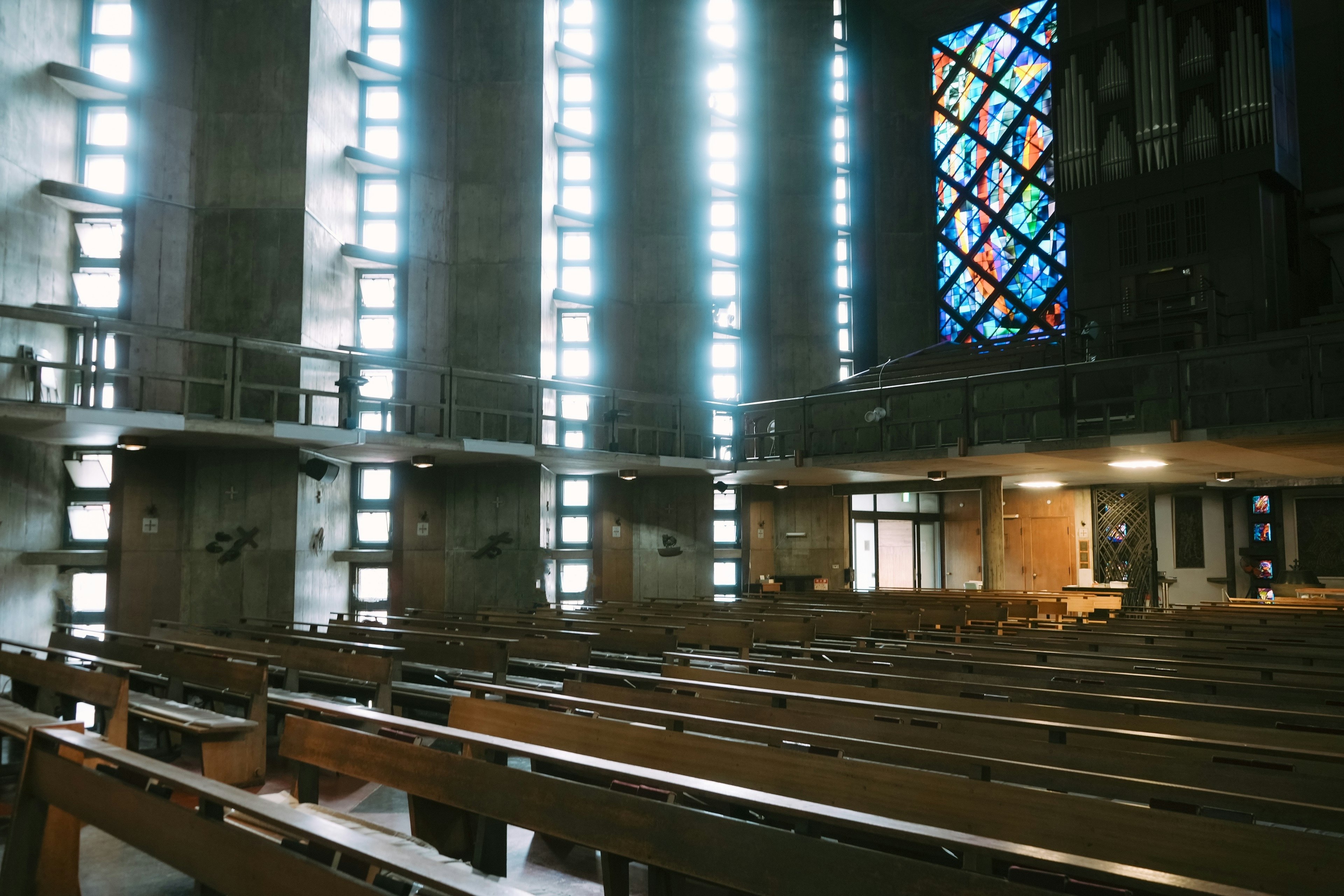 Interior of a church with bright light streaming in wooden benches and stunning stained glass