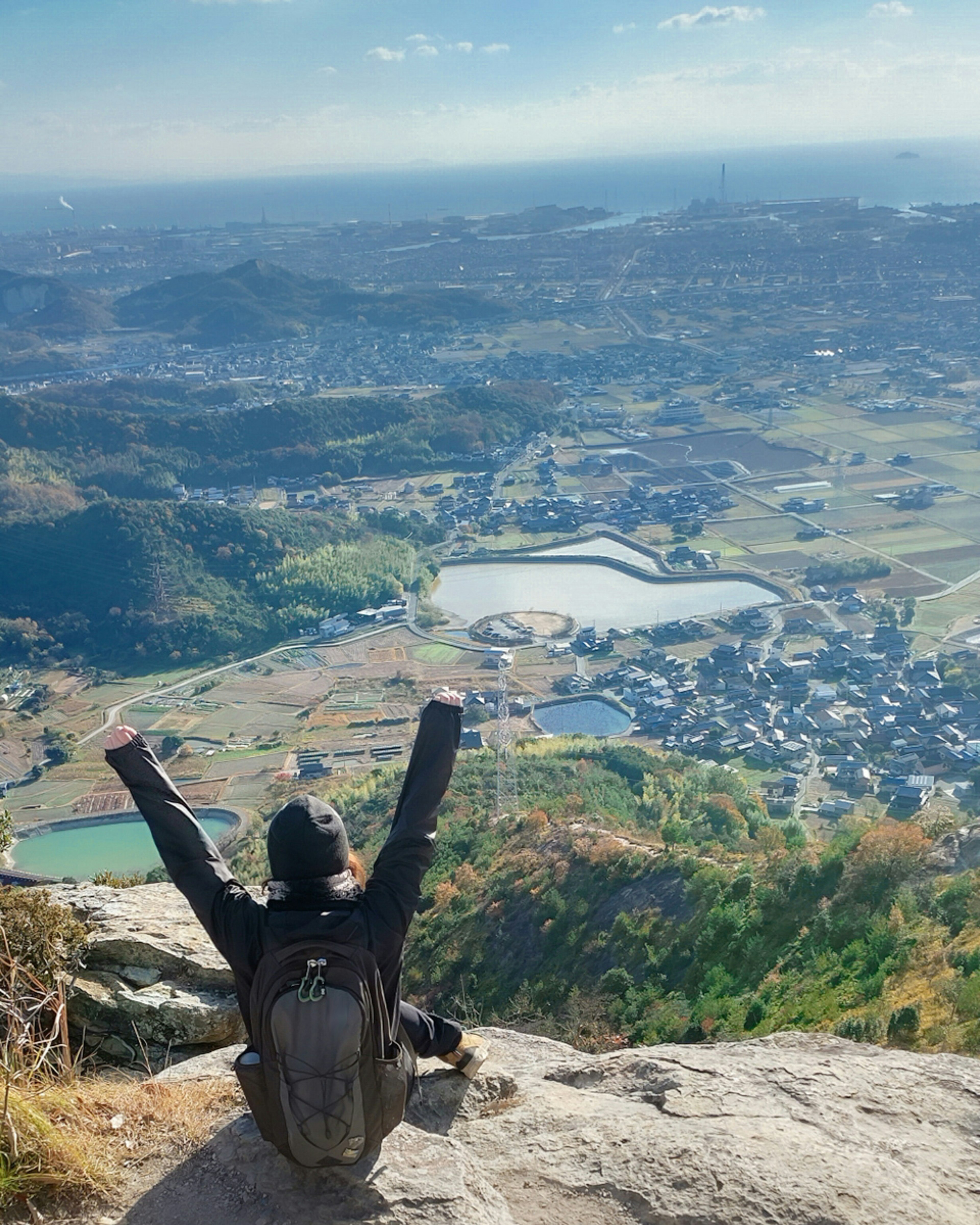 Panjat gunung duduk dengan tangan terangkat menikmati pemandangan