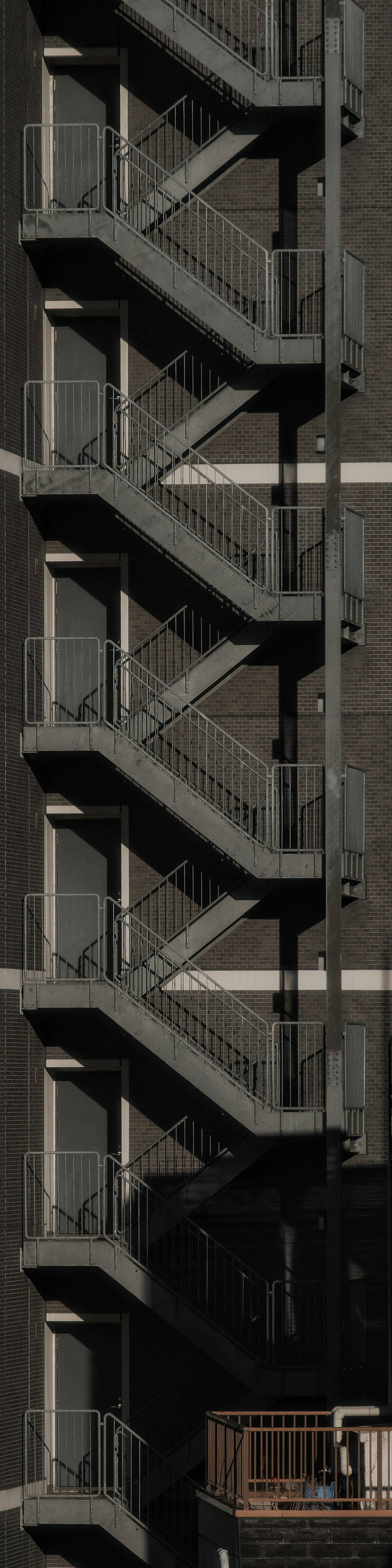 Escalera de metal en espiral unida a un edificio con exterior oscuro