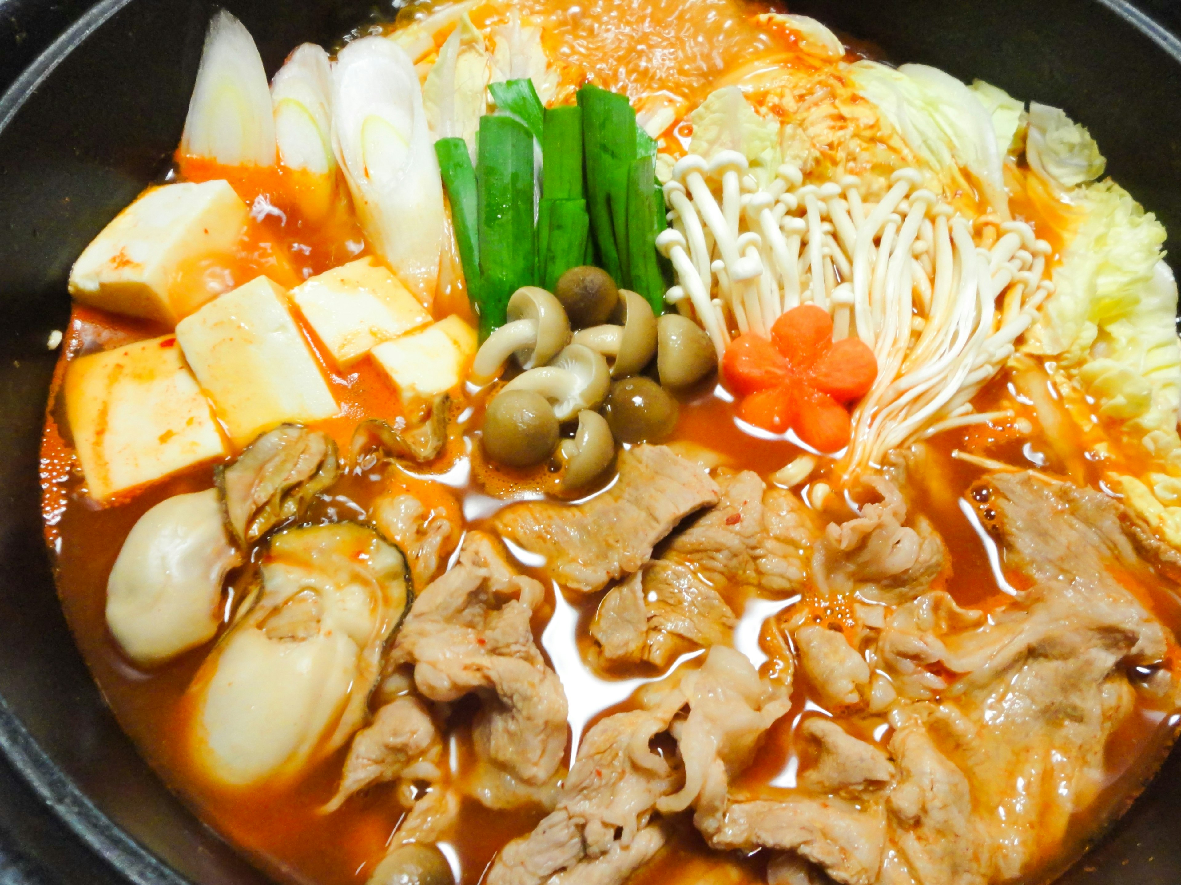 Un plat de fondue coloré avec de la viande, des légumes et du tofu