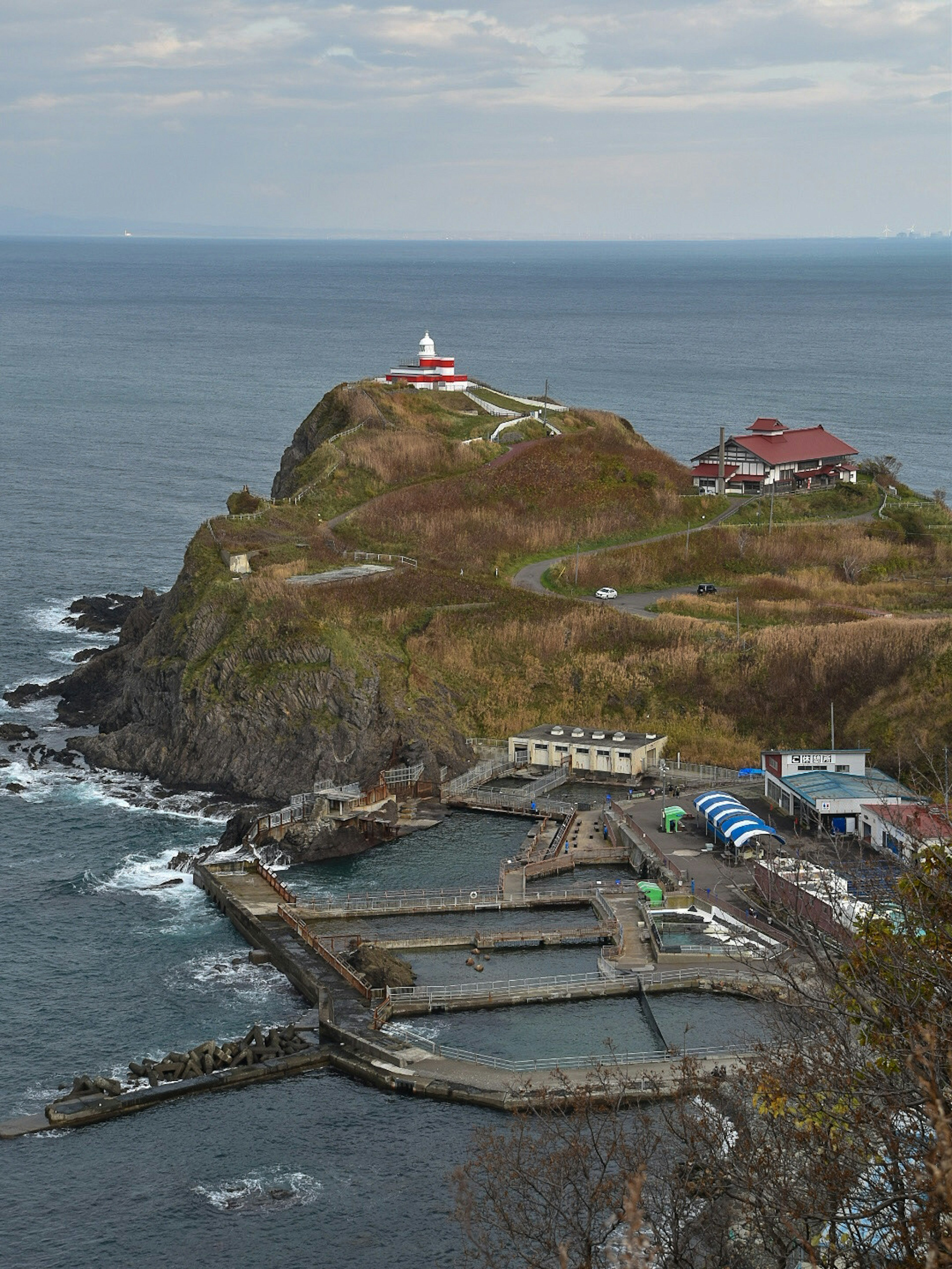 Scenic view of a coastal cape with a lighthouse and hot spring facilities