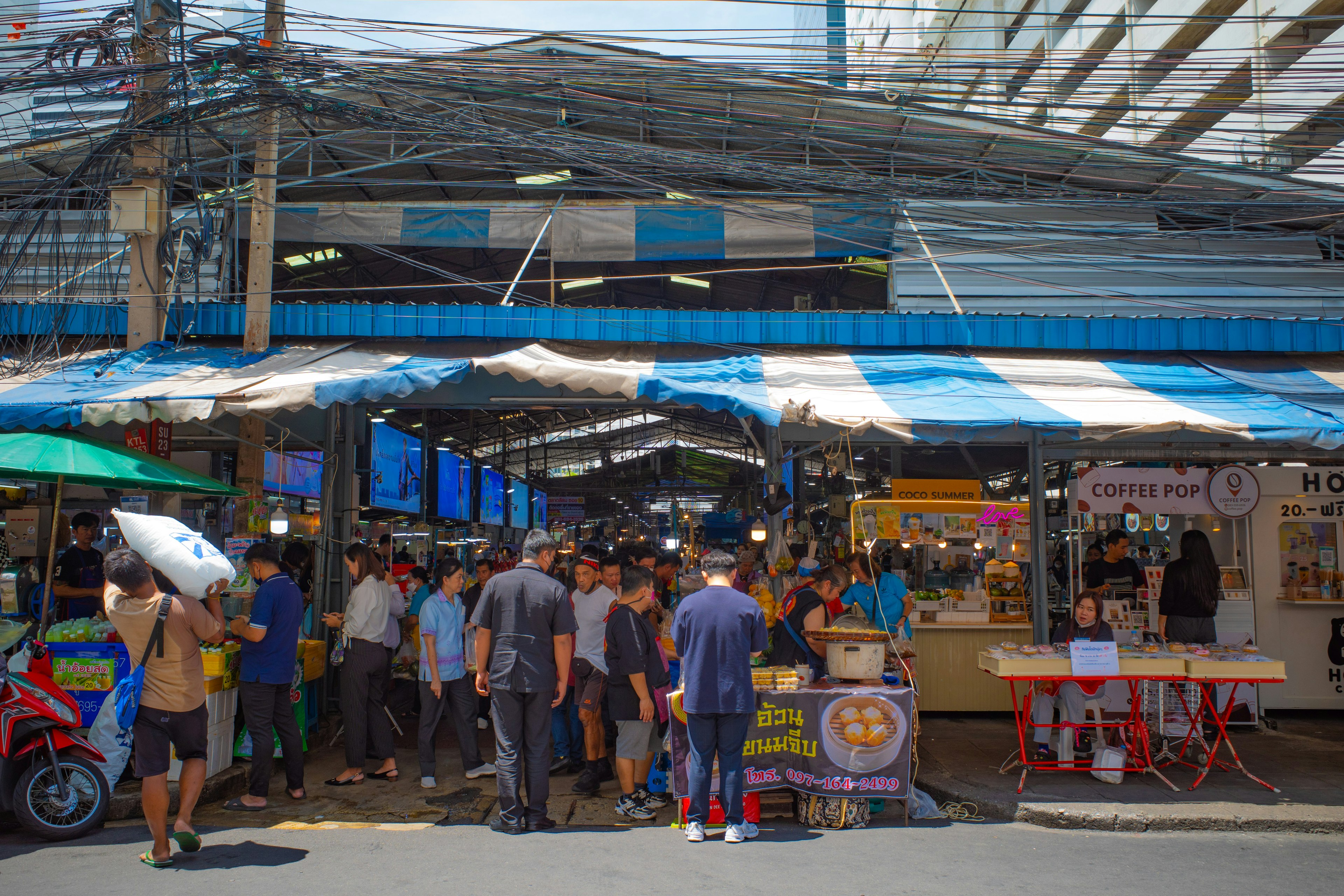 Bustling market scene with food stalls and crowds of people enjoying local delicacies