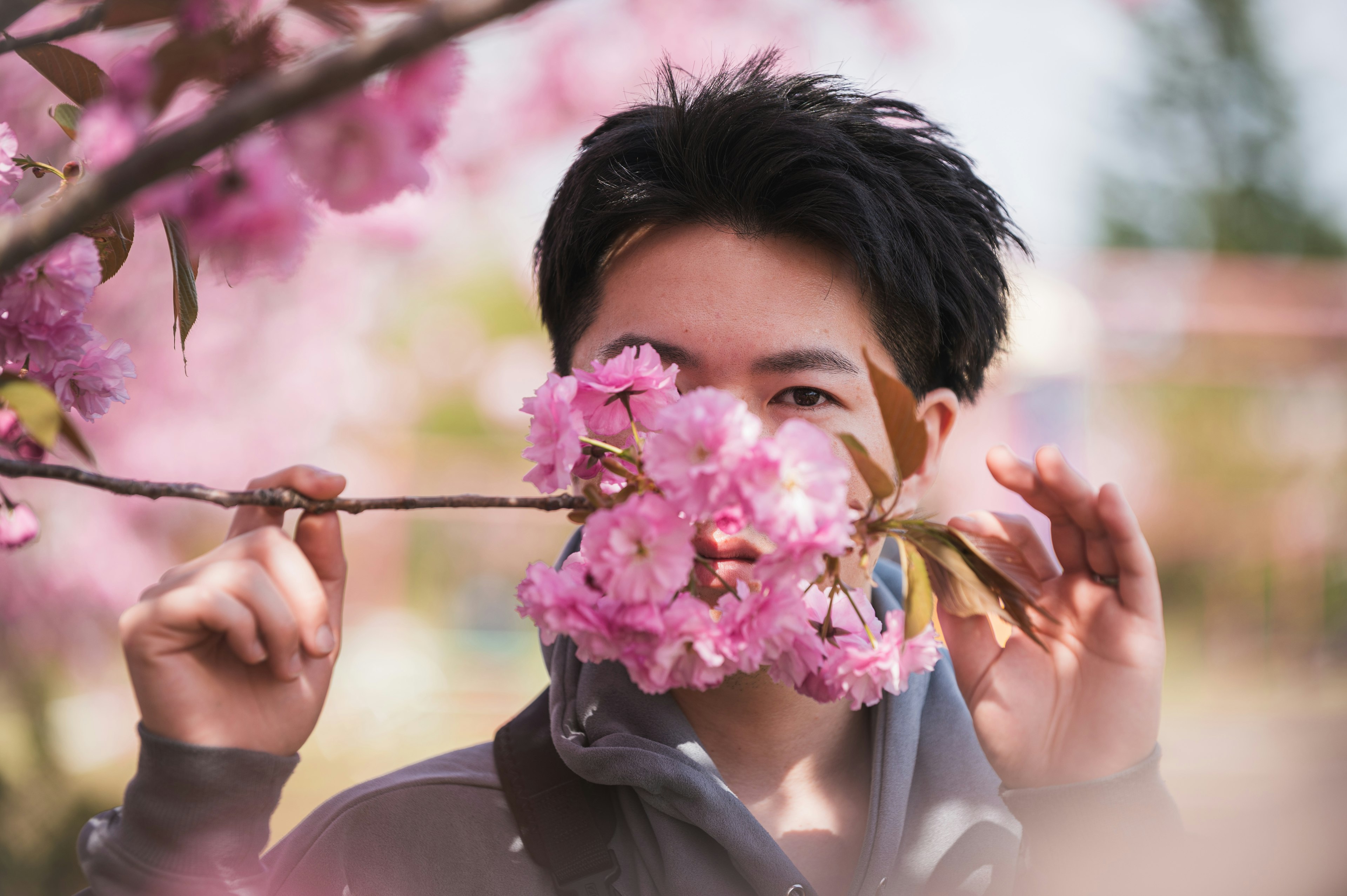 桜の花の前でポーズを取る若い男性の写真