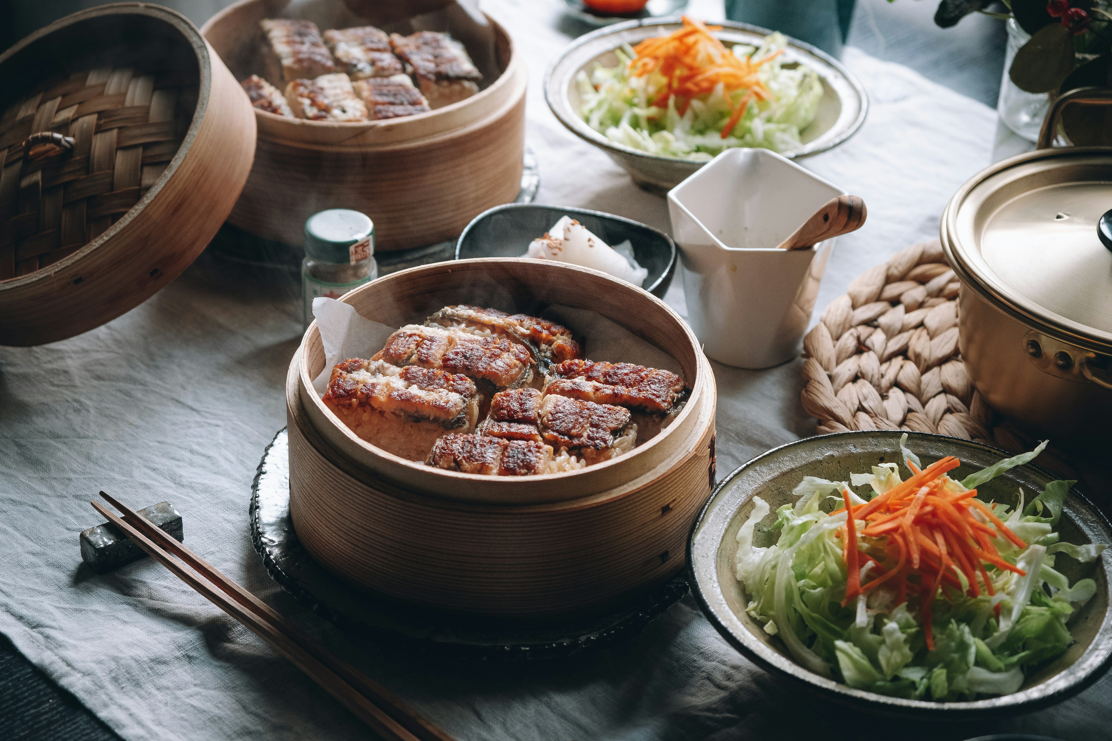 Table setting with bamboo steamer dishes and fresh salad