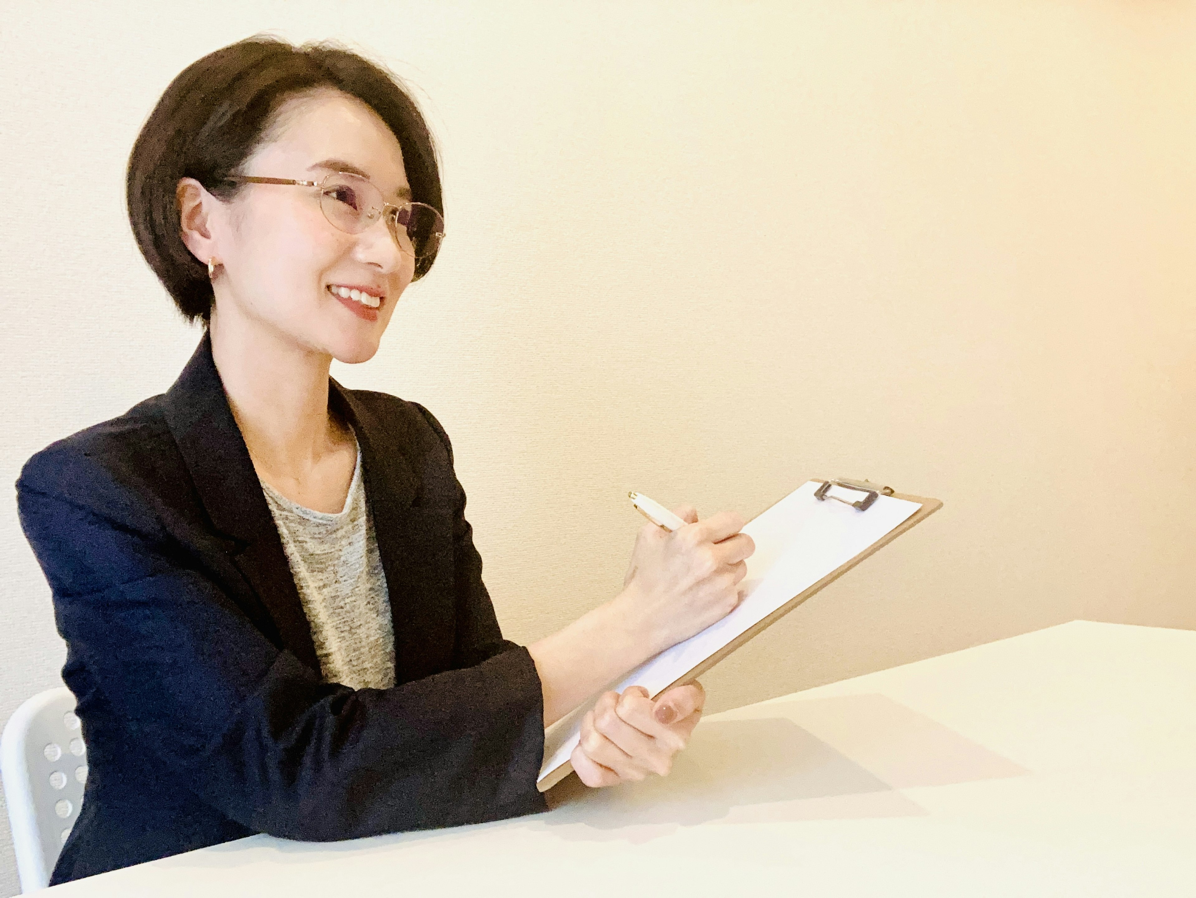 Una mujer sonriendo mientras toma notas en un clipboard