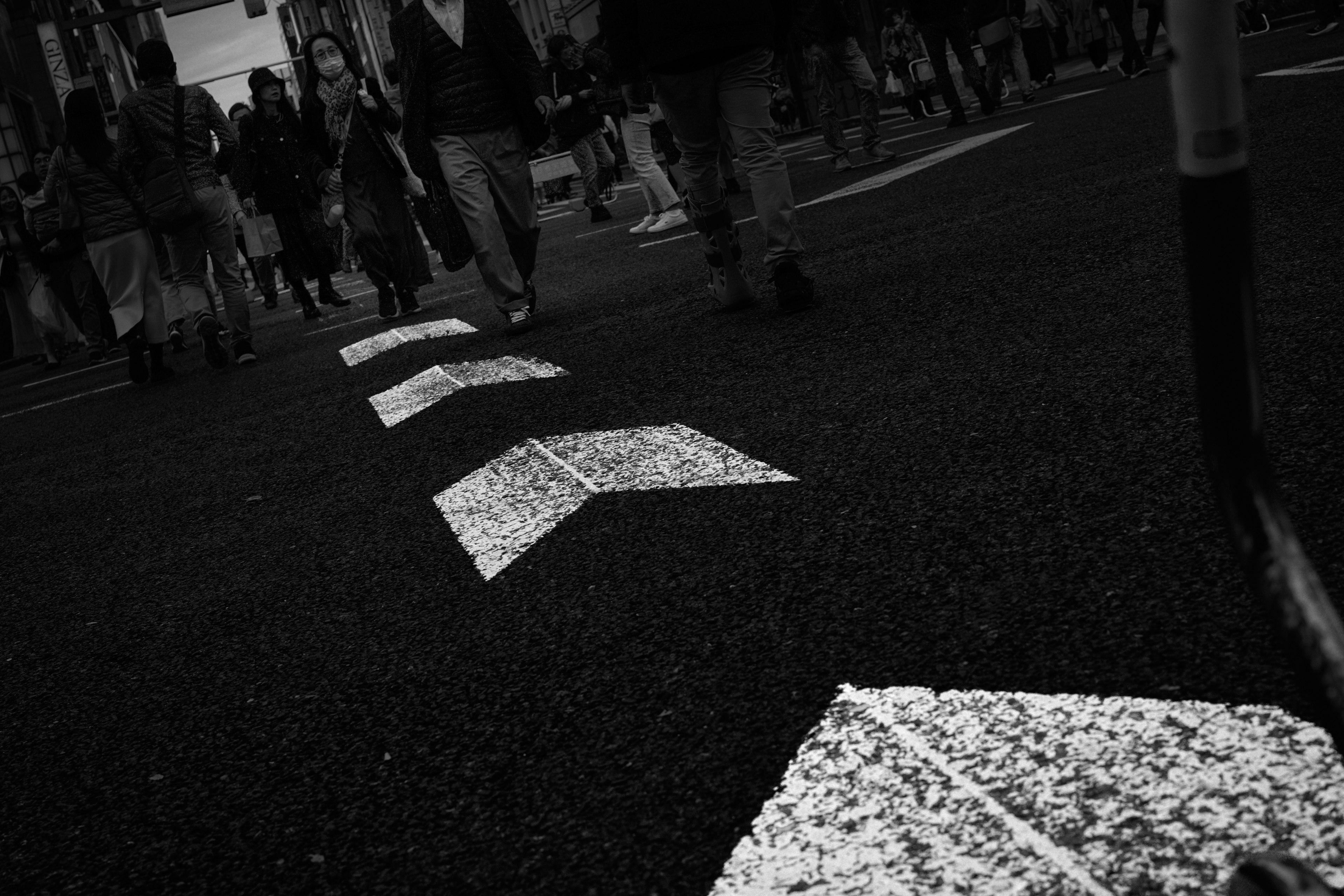 Primo piano di frecce bianche su una strada con persone che camminano