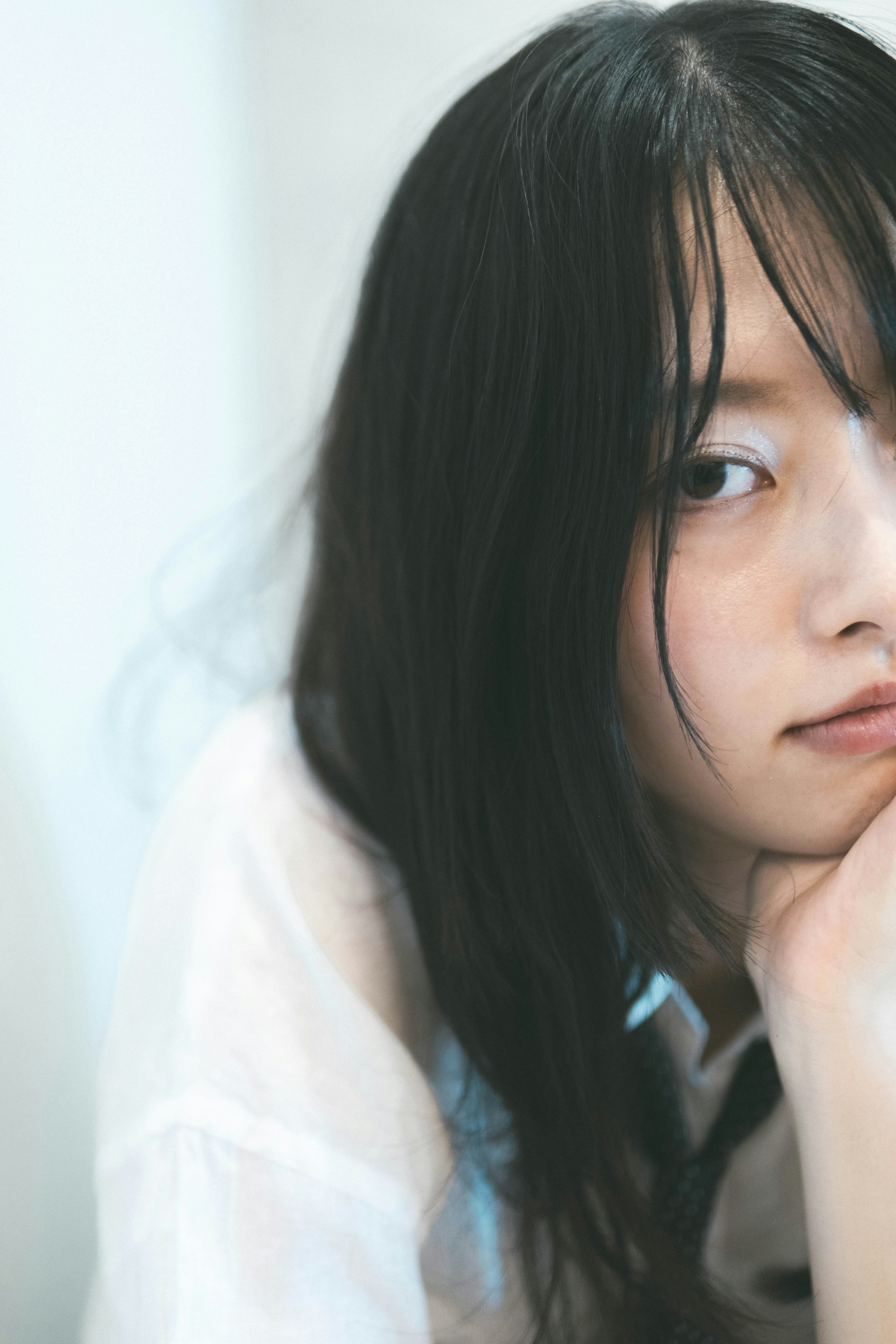 Una giovane donna che poggia il mento sulla mano con lunghi capelli neri che fluiscono accanto al viso