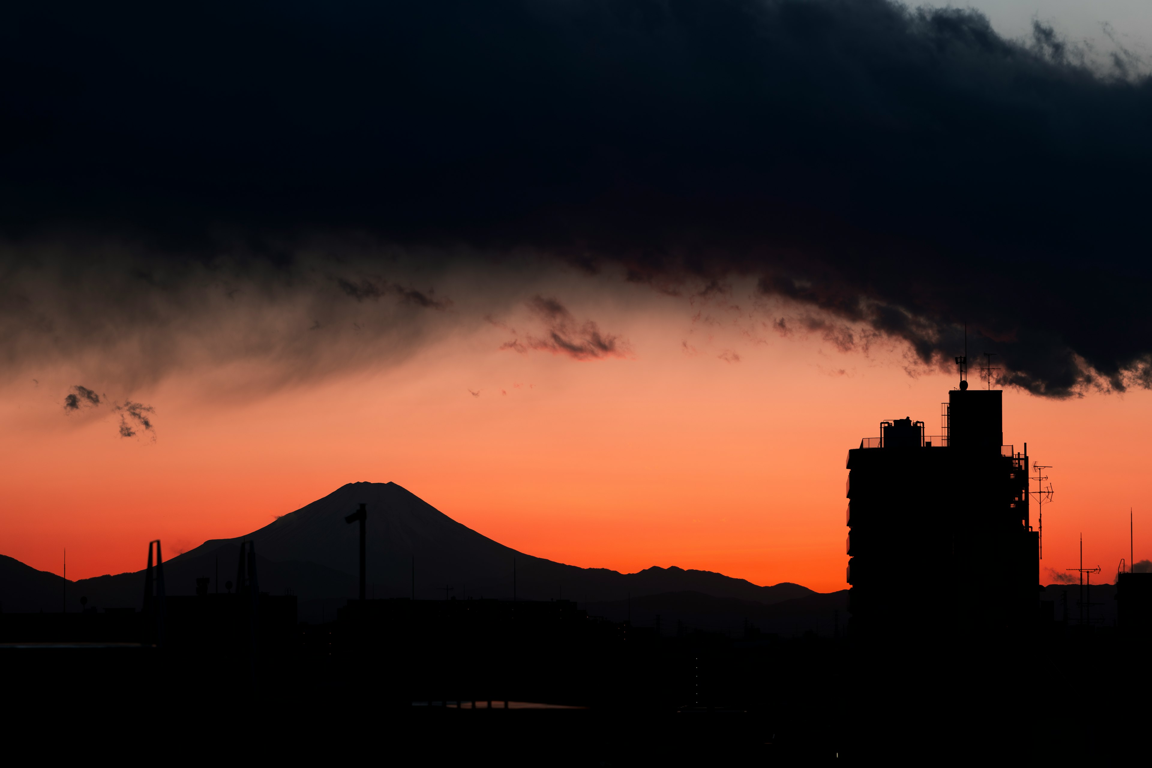 Silhouette del Monte Fuji e di una fabbrica contro un cielo al tramonto