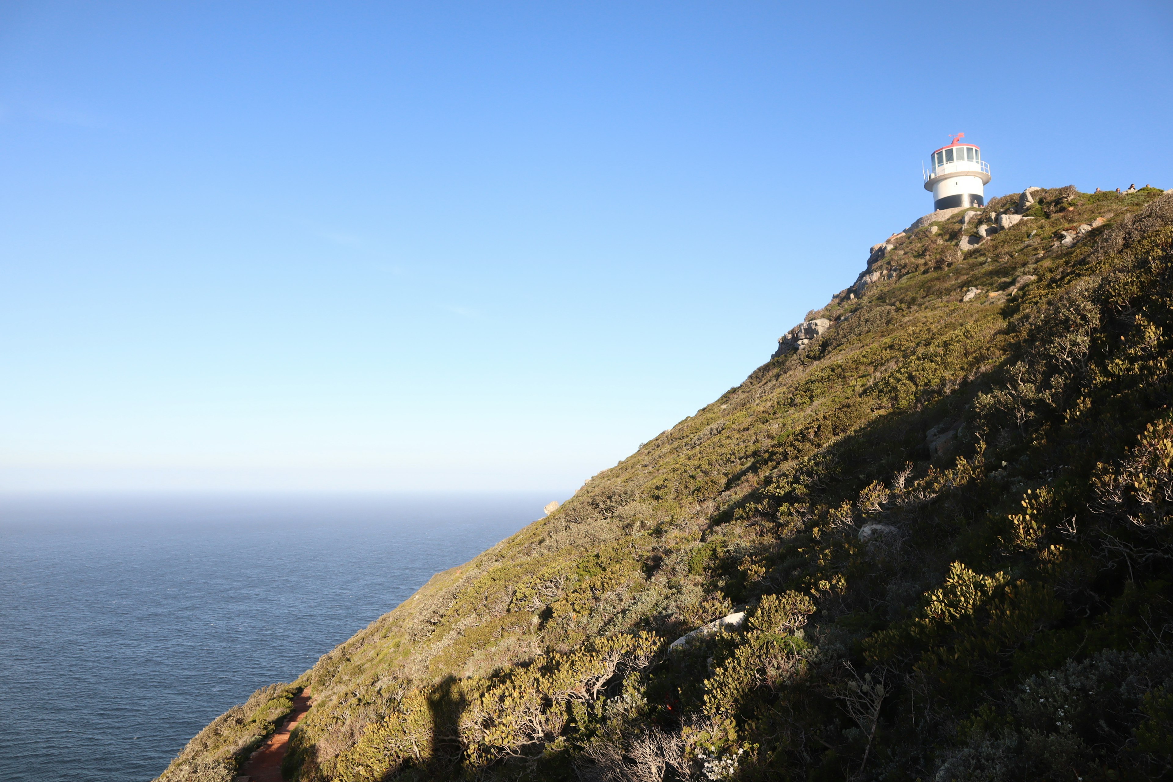 Imagen de un faro en una colina con vista al mar