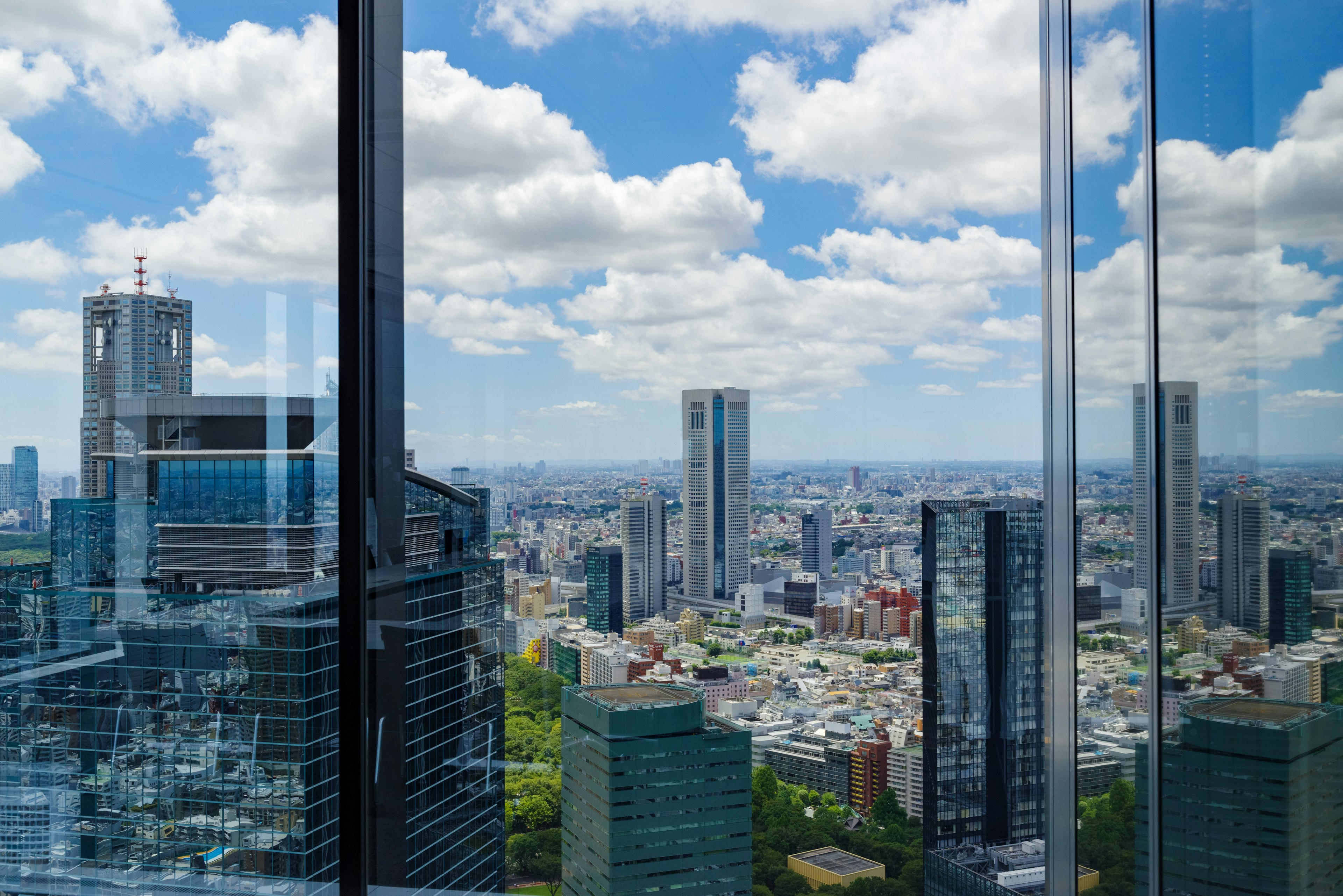 Pemandangan dari gedung pencakar langit di Tokyo yang menunjukkan langit biru dan awan putih di atas cakrawala kota