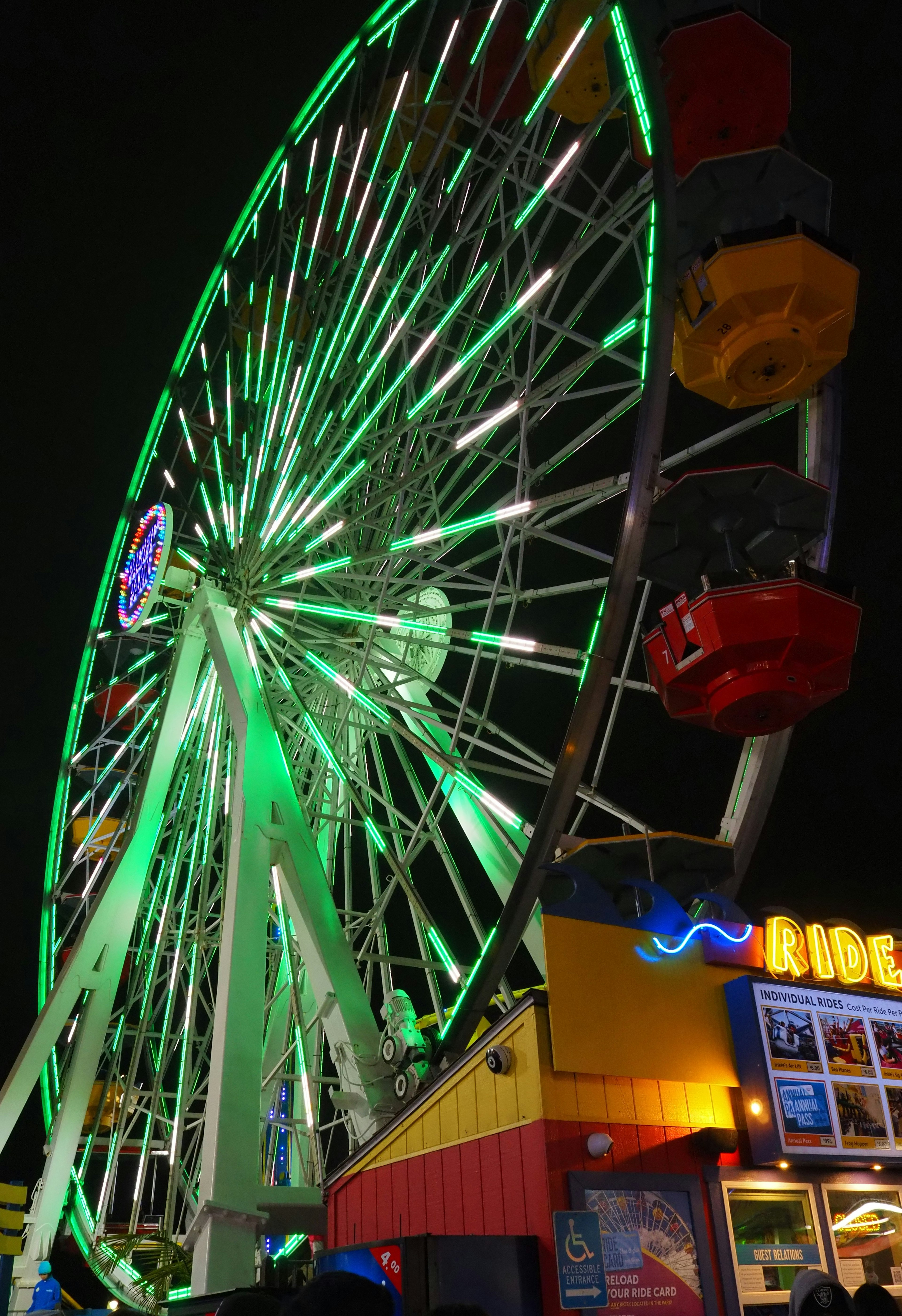 Rueda de la fortuna iluminada de verde por la noche con góndolas coloridas