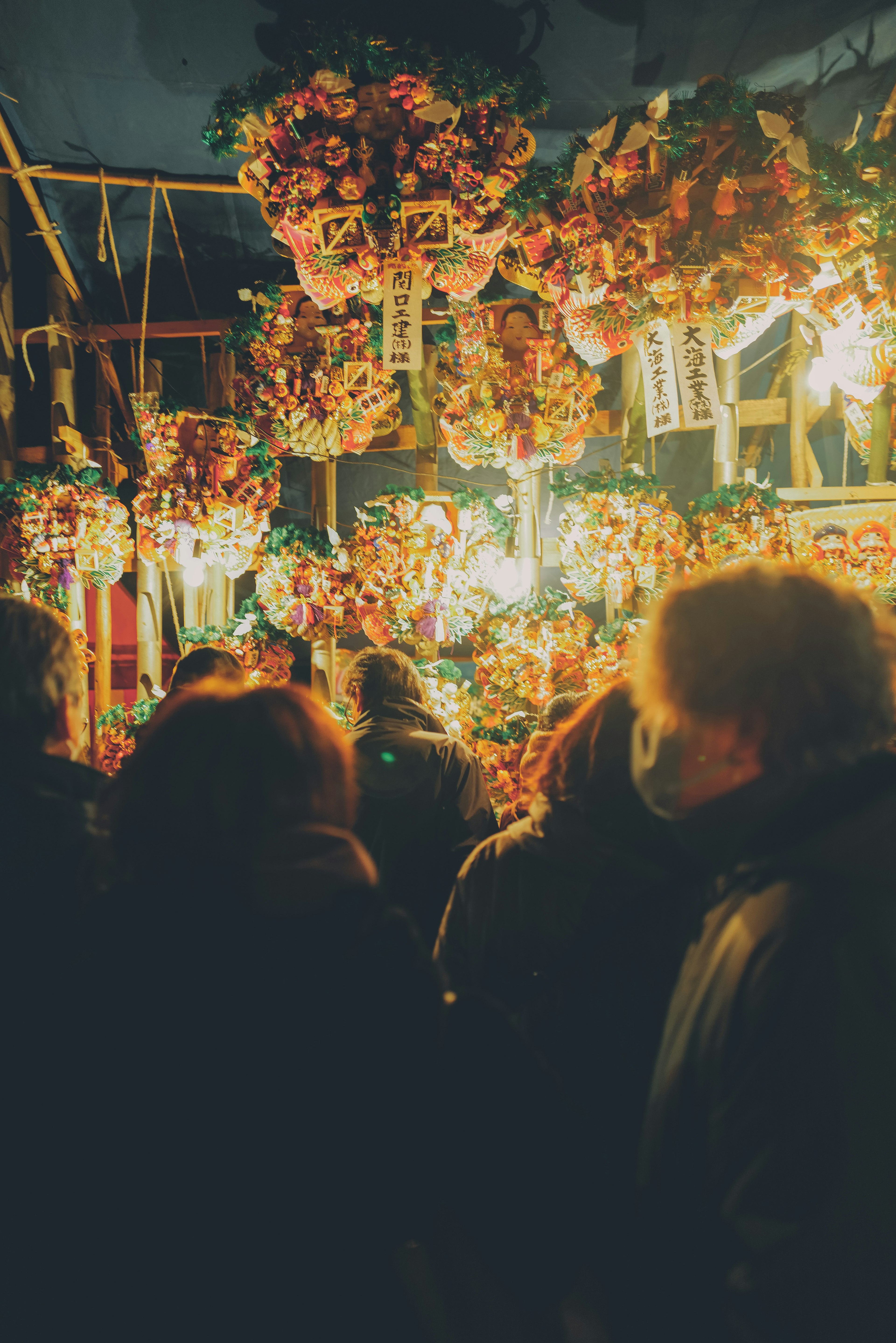 Personas rodeadas de flores y luces en un mercado nocturno