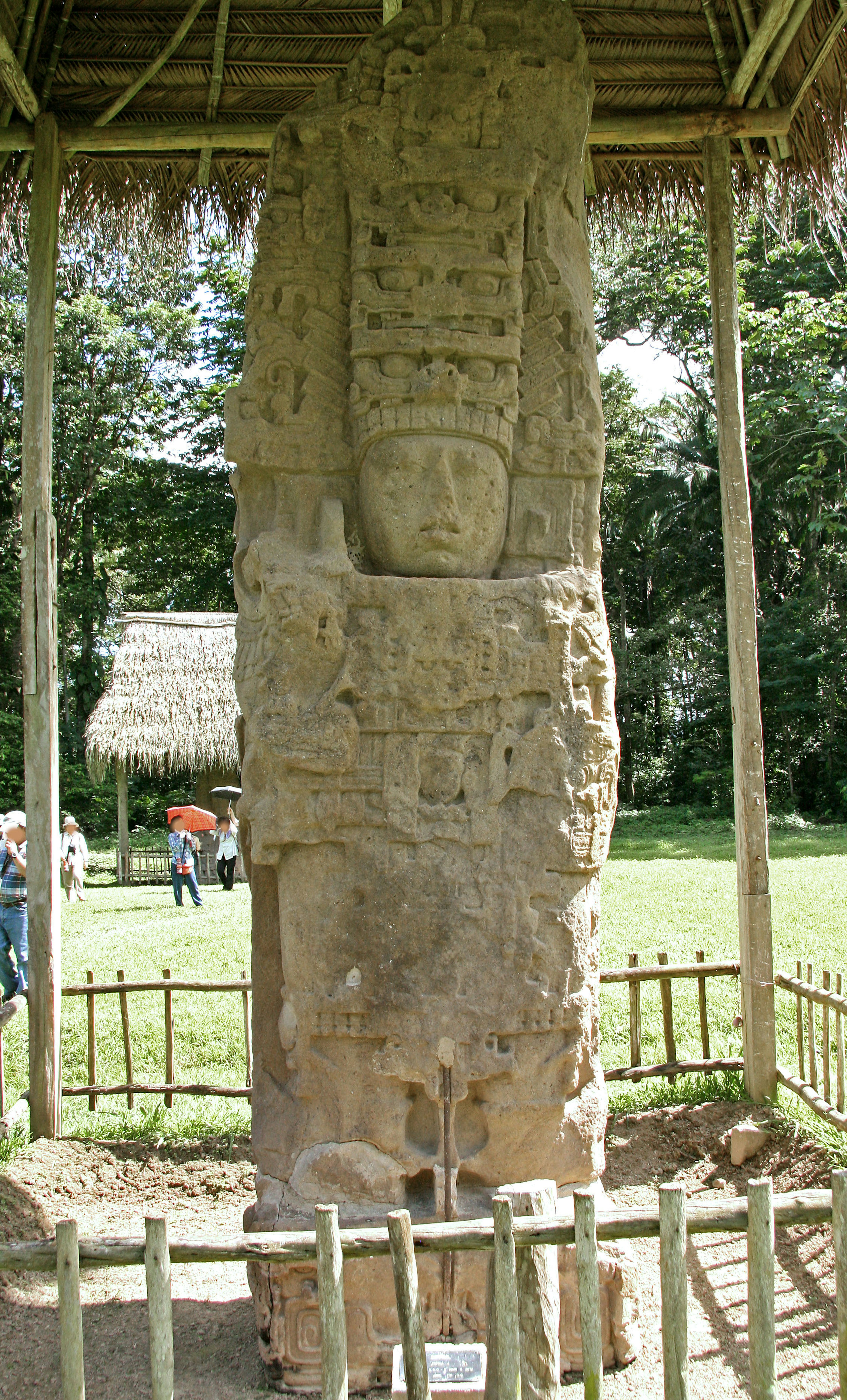 Estatua de piedra antigua de una deidad rodeada por una cerca de bambú