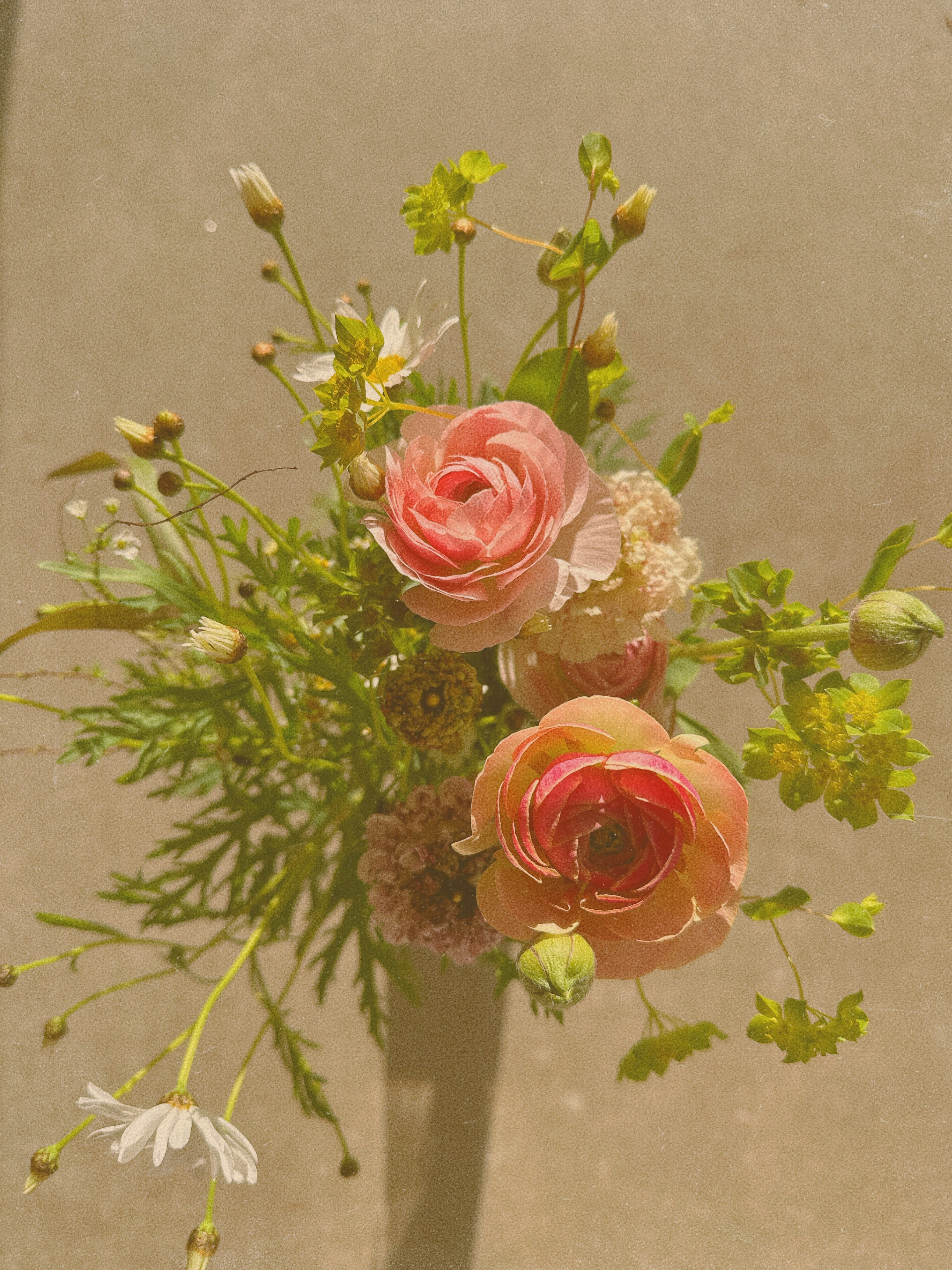 Arrangement of pink ranunculus and wildflowers