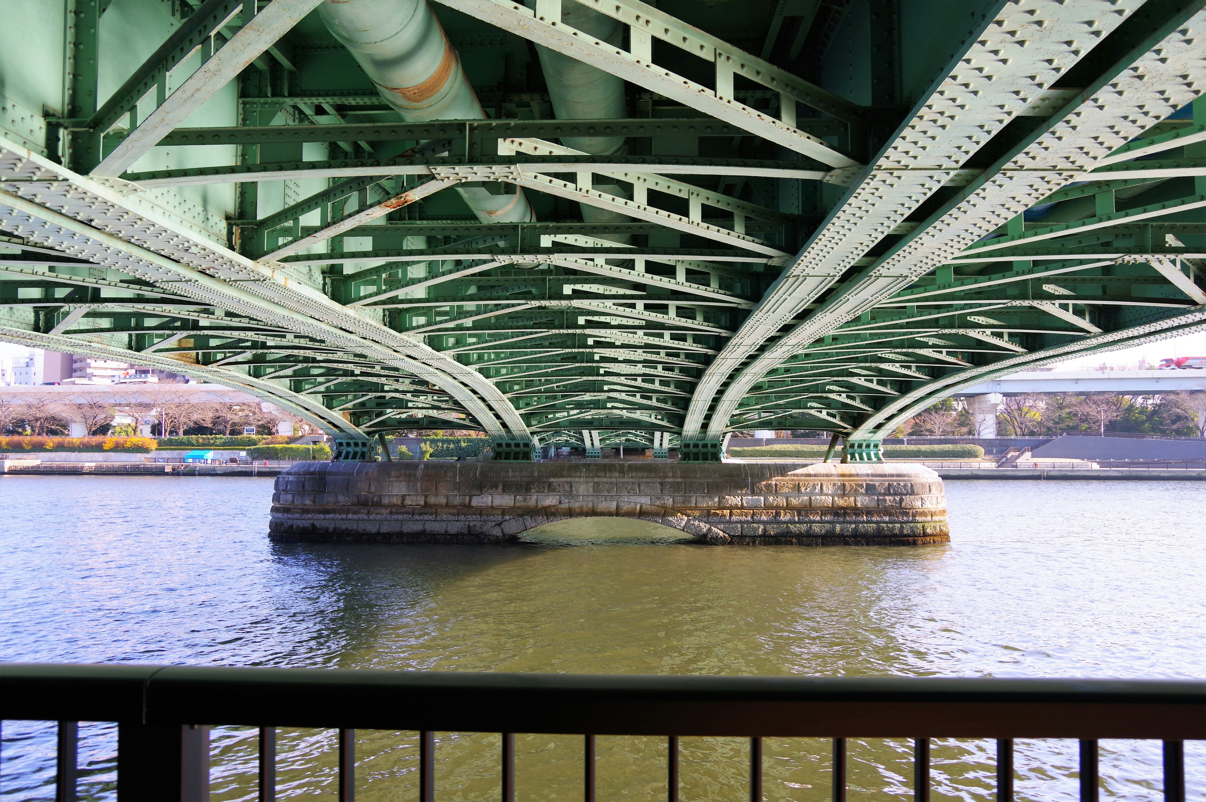 Puente verde visto desde abajo mostrando el diseño estructural sobre el agua