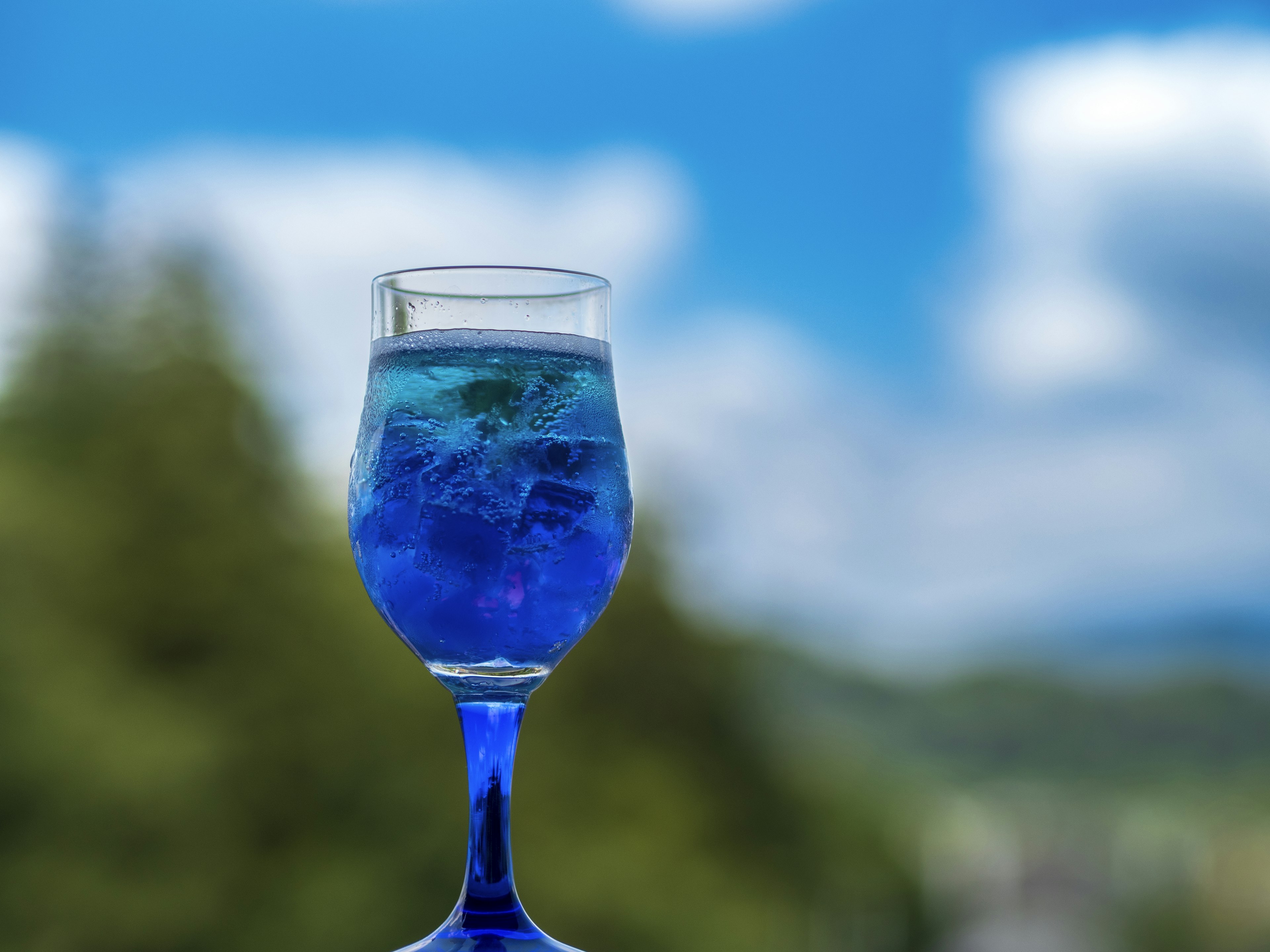 Ein schöner blauer Drink in einem Glas mit blauem Himmel im Hintergrund