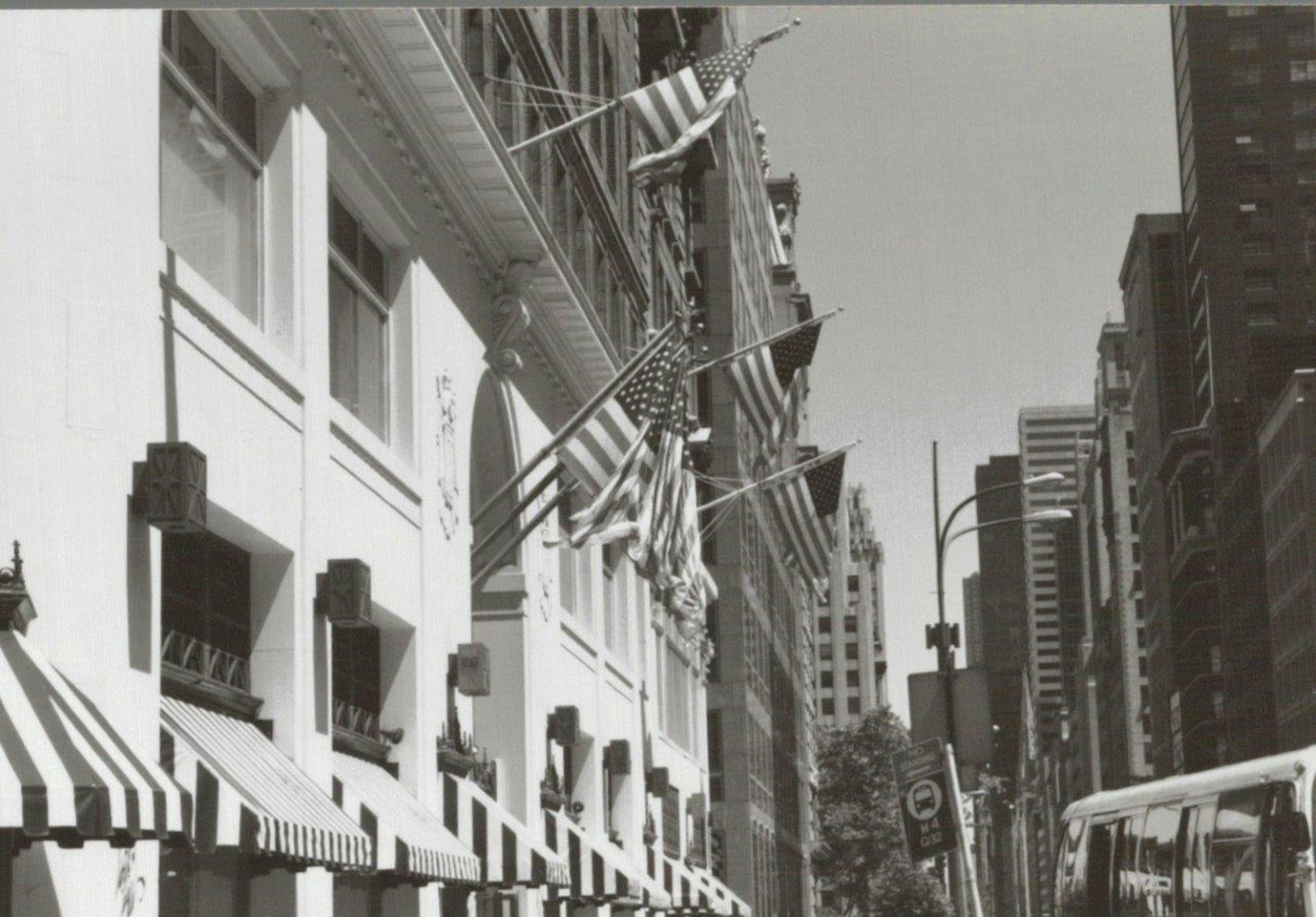 Black and white image of a building facade with American flags displayed