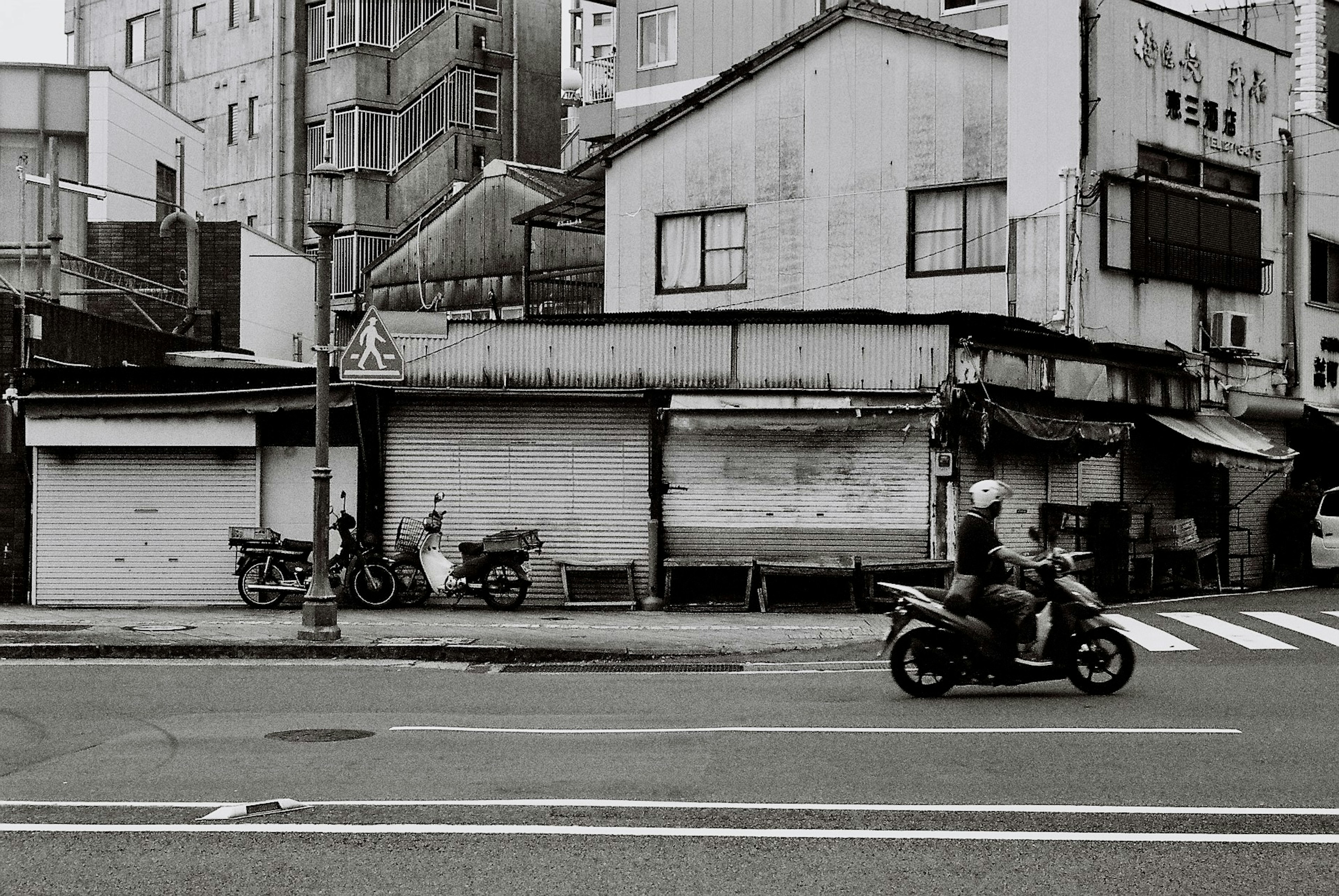 Scène de rue en noir et blanc avec des bâtiments anciens et des motos garées