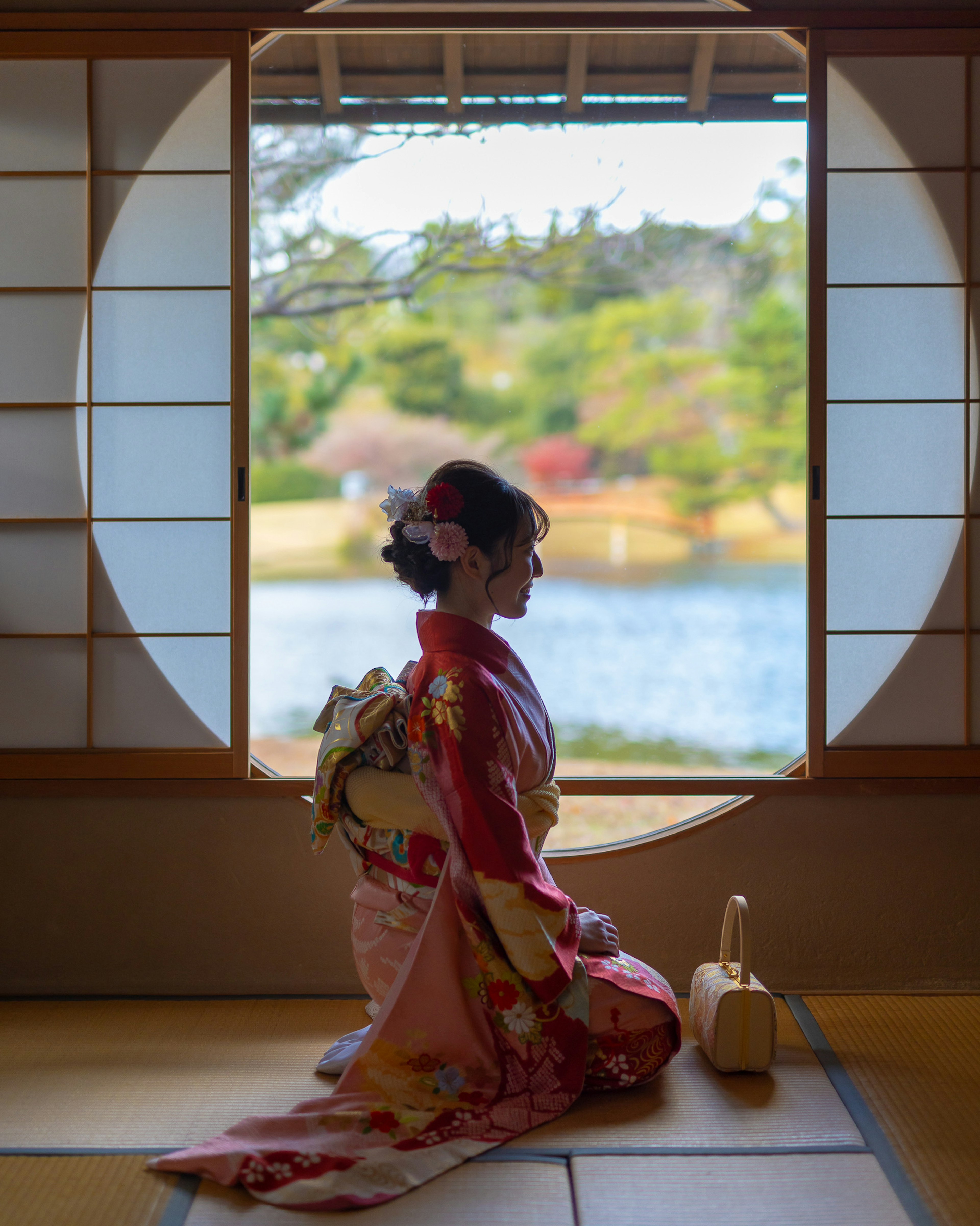 Una mujer en un hermoso kimono sentada frente a una ventana circular