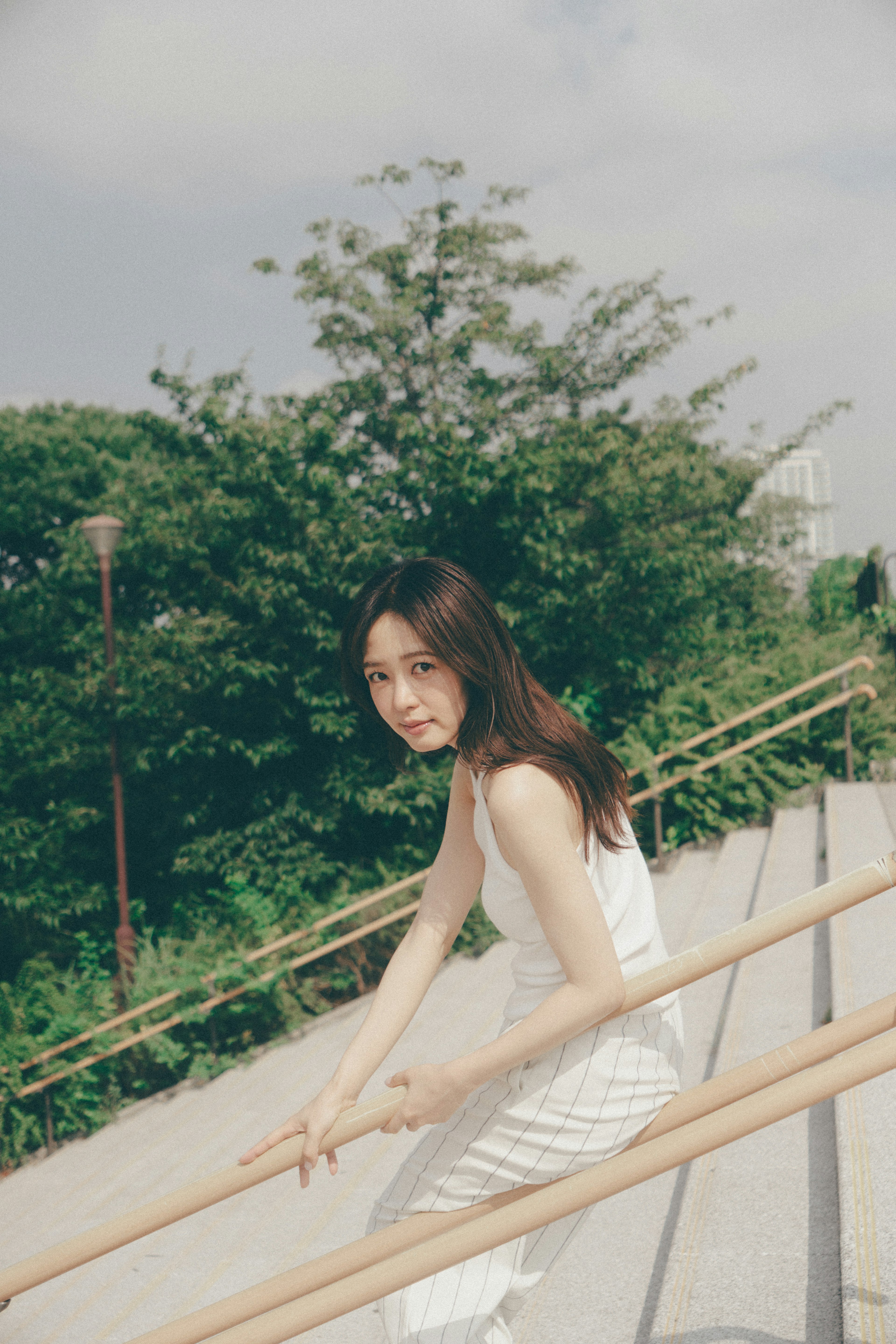 Woman in a white dress descending stairs with a green background