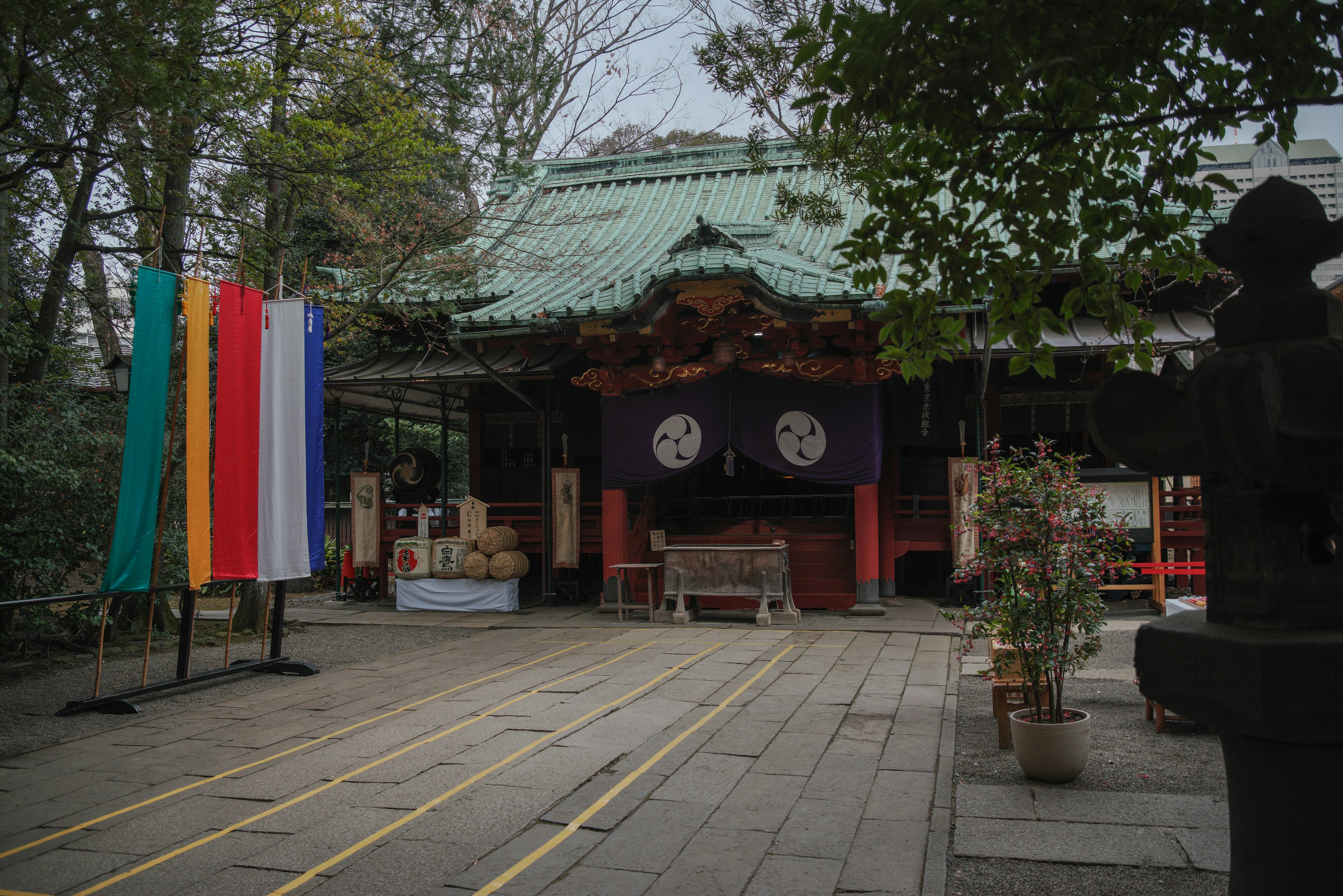 A shrine building with a green roof and colorful flags standing in front