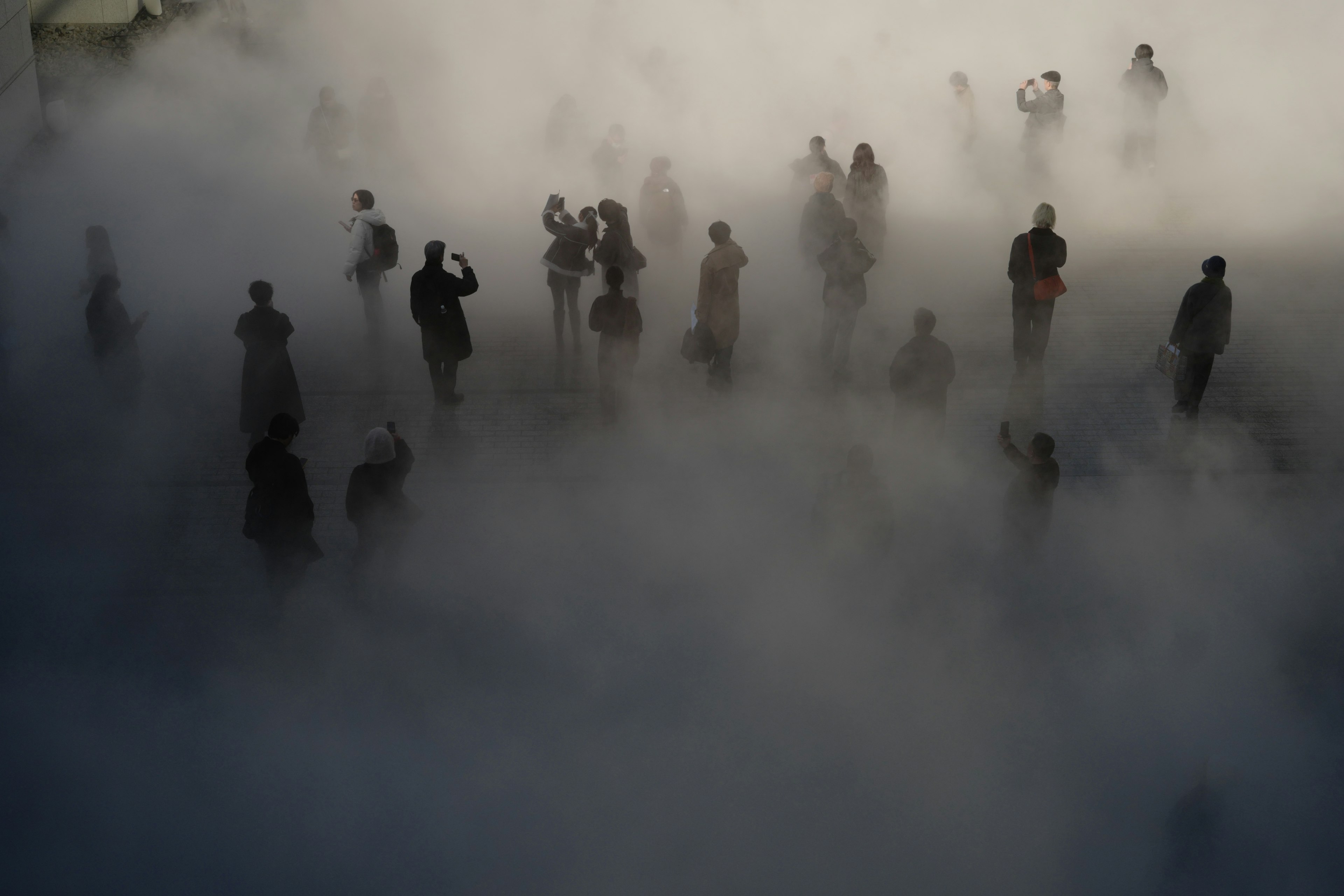 霧の中に立つ人々のシルエットが見える風景