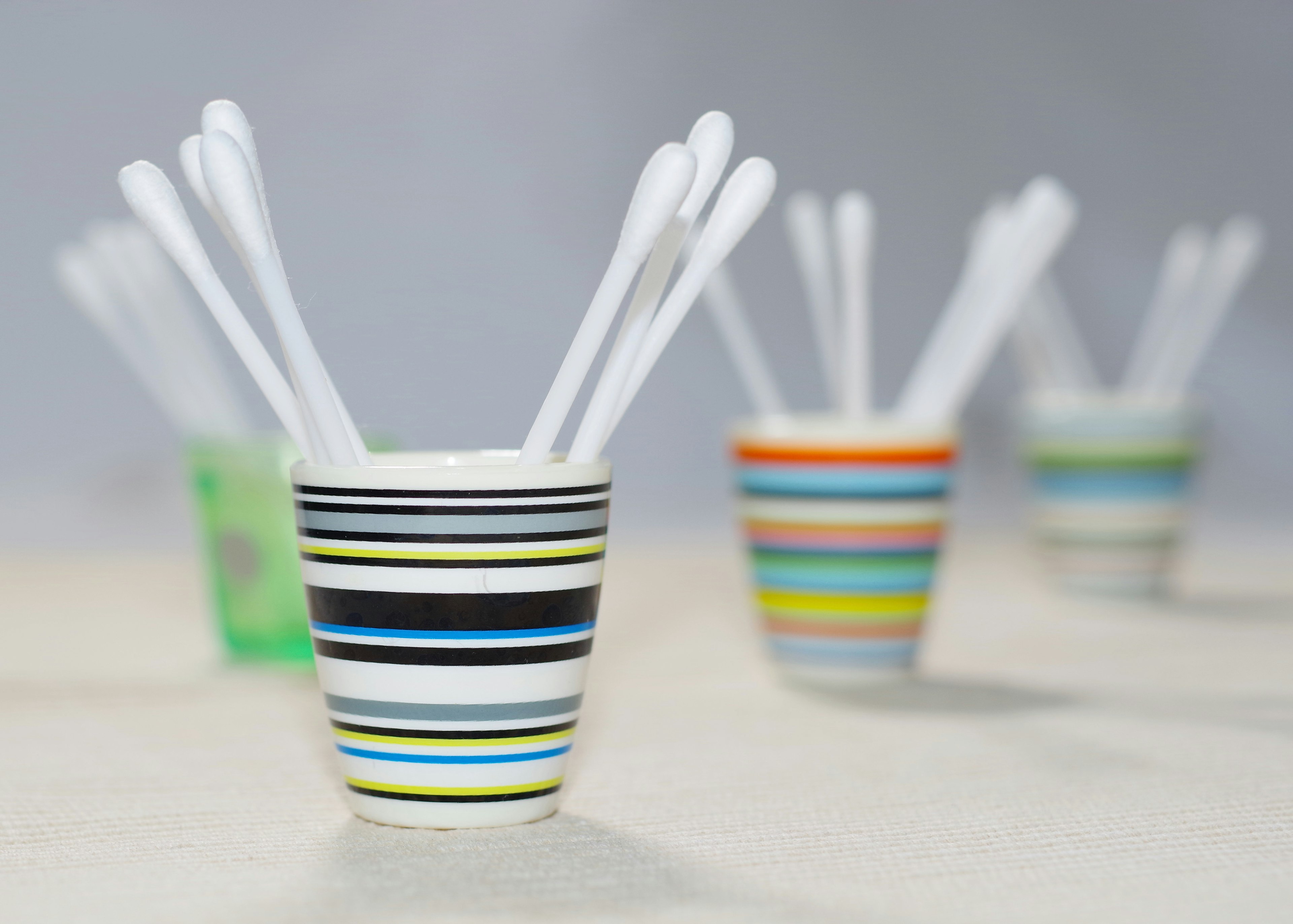 Colorful striped cup with white sticks standing inside