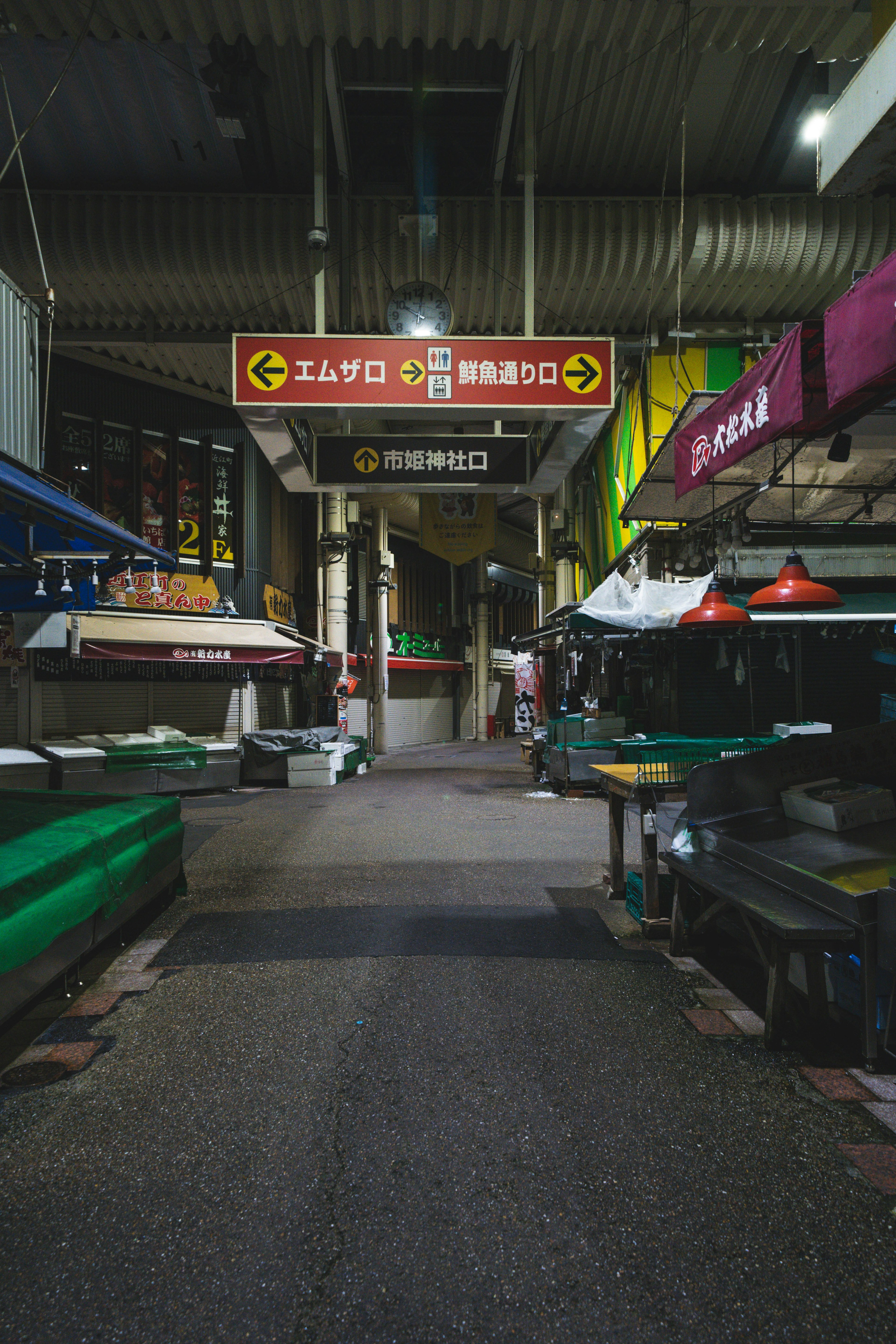 A view of a market aisle with stalls and signs overhead