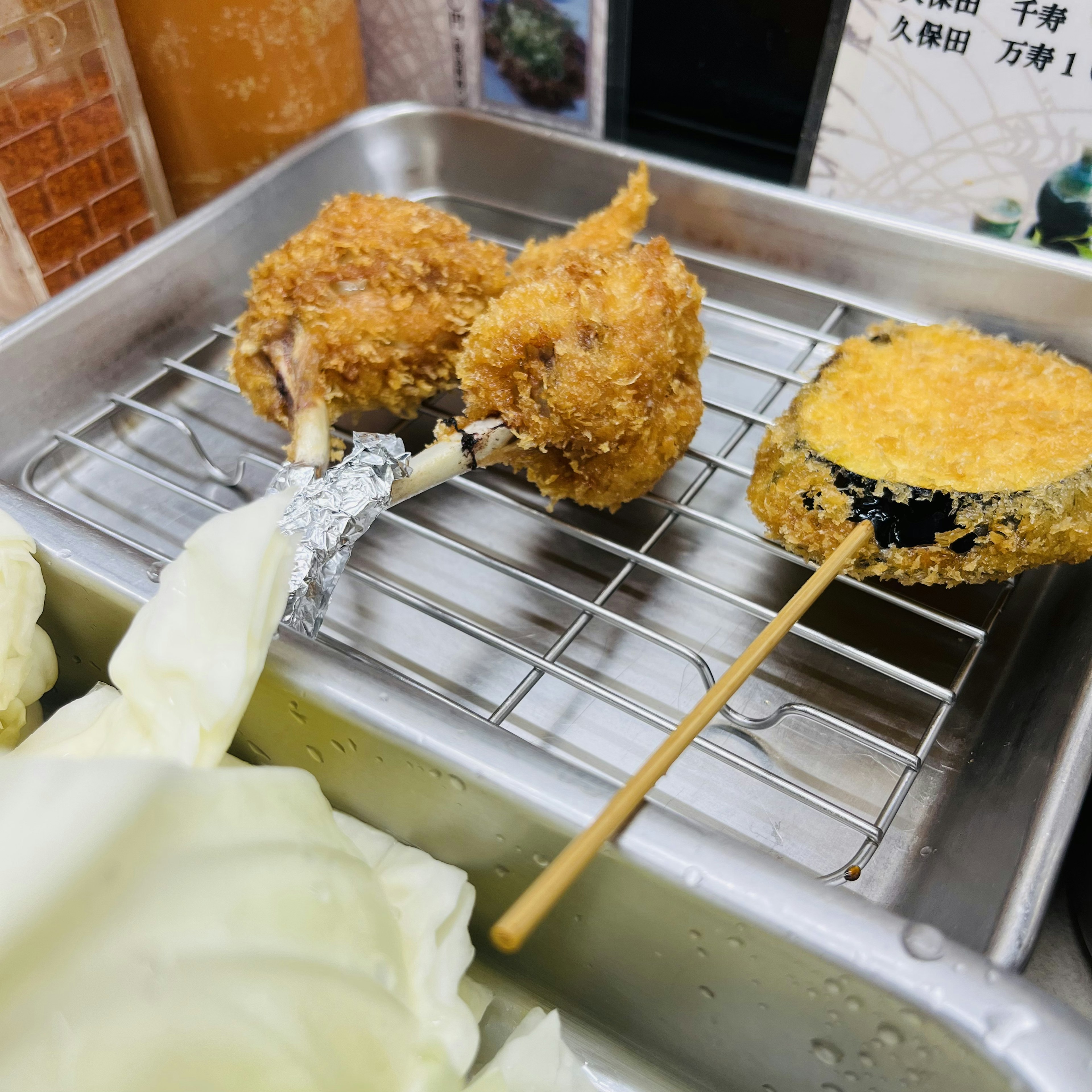 揚げ物の盛り合わせ、カリカリの鶏肉、串刺しの野菜、キャベツの葉