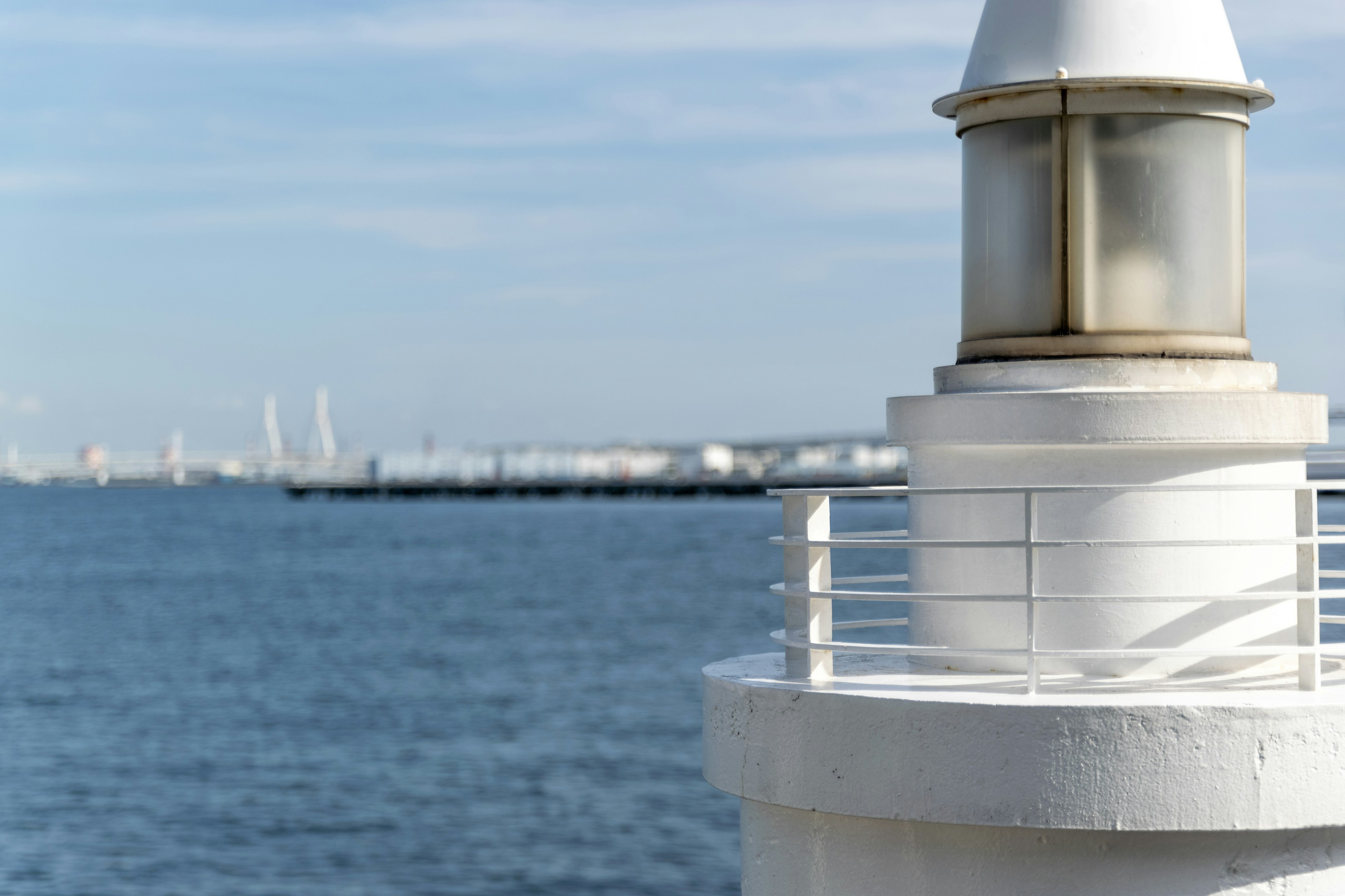 Primo piano di un faro bianco con l'oceano sullo sfondo