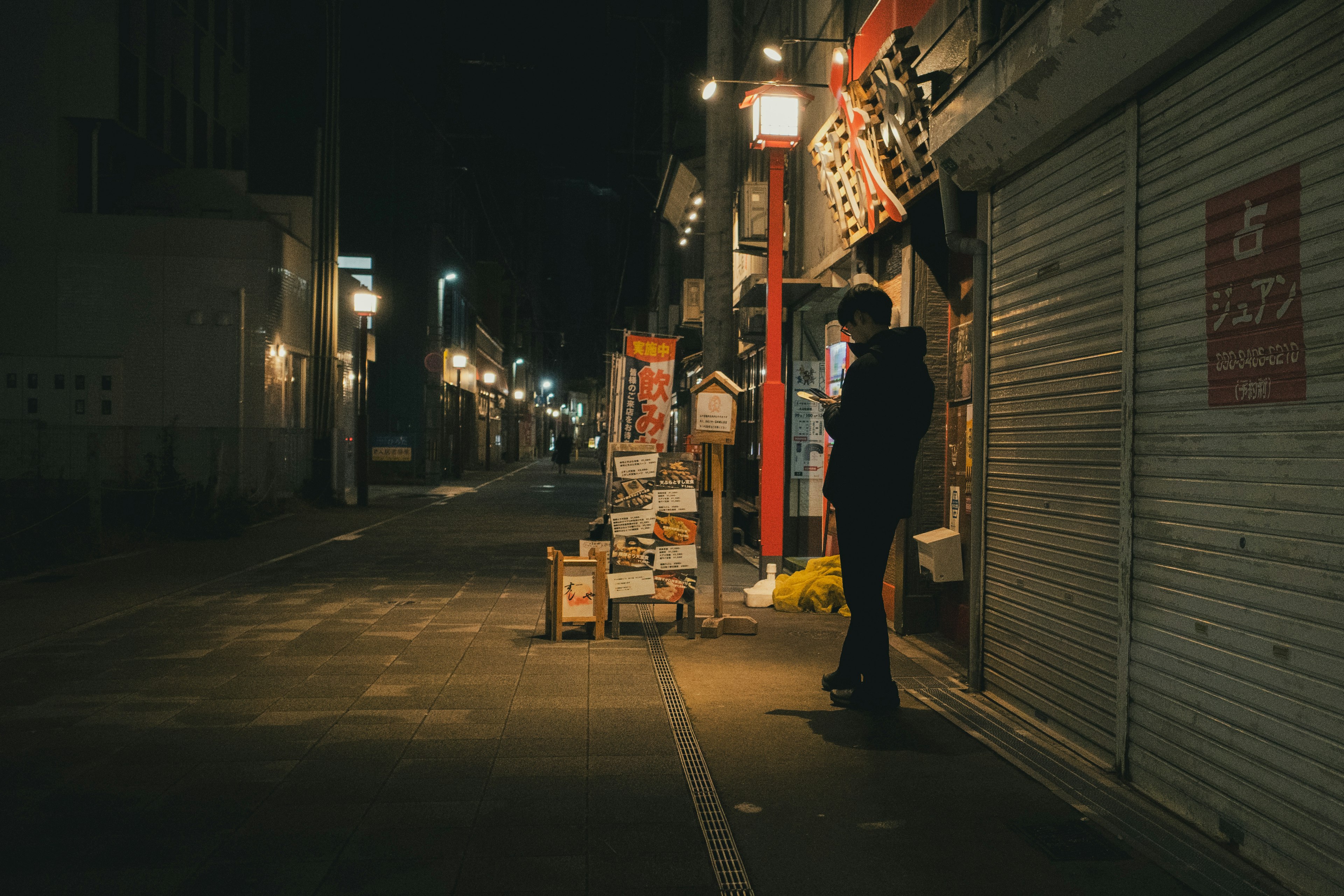 夜晚在狭窄街角站着的人和明亮的招牌