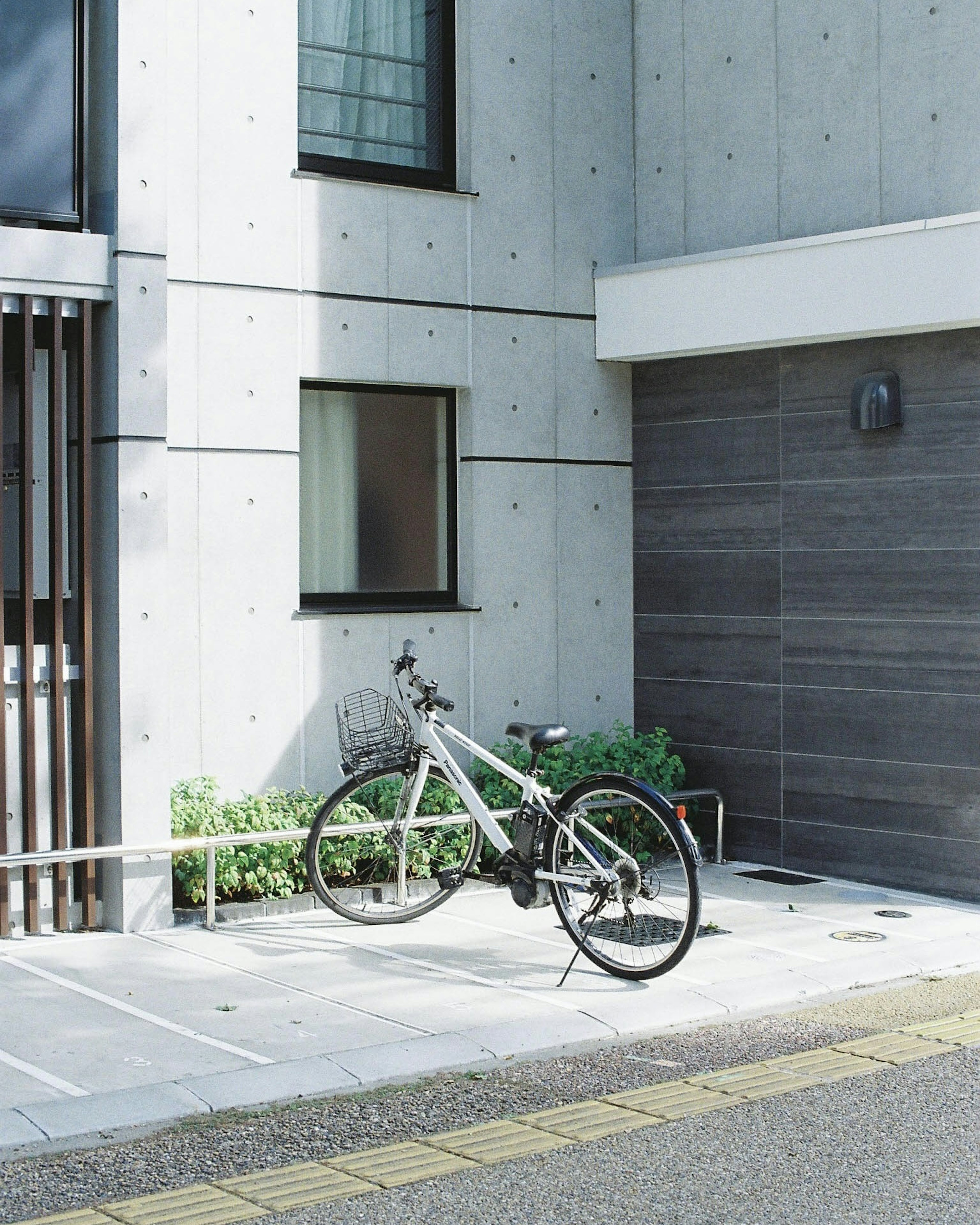 Una bicicleta blanca estacionada frente a una pared de concreto con plantas verdes