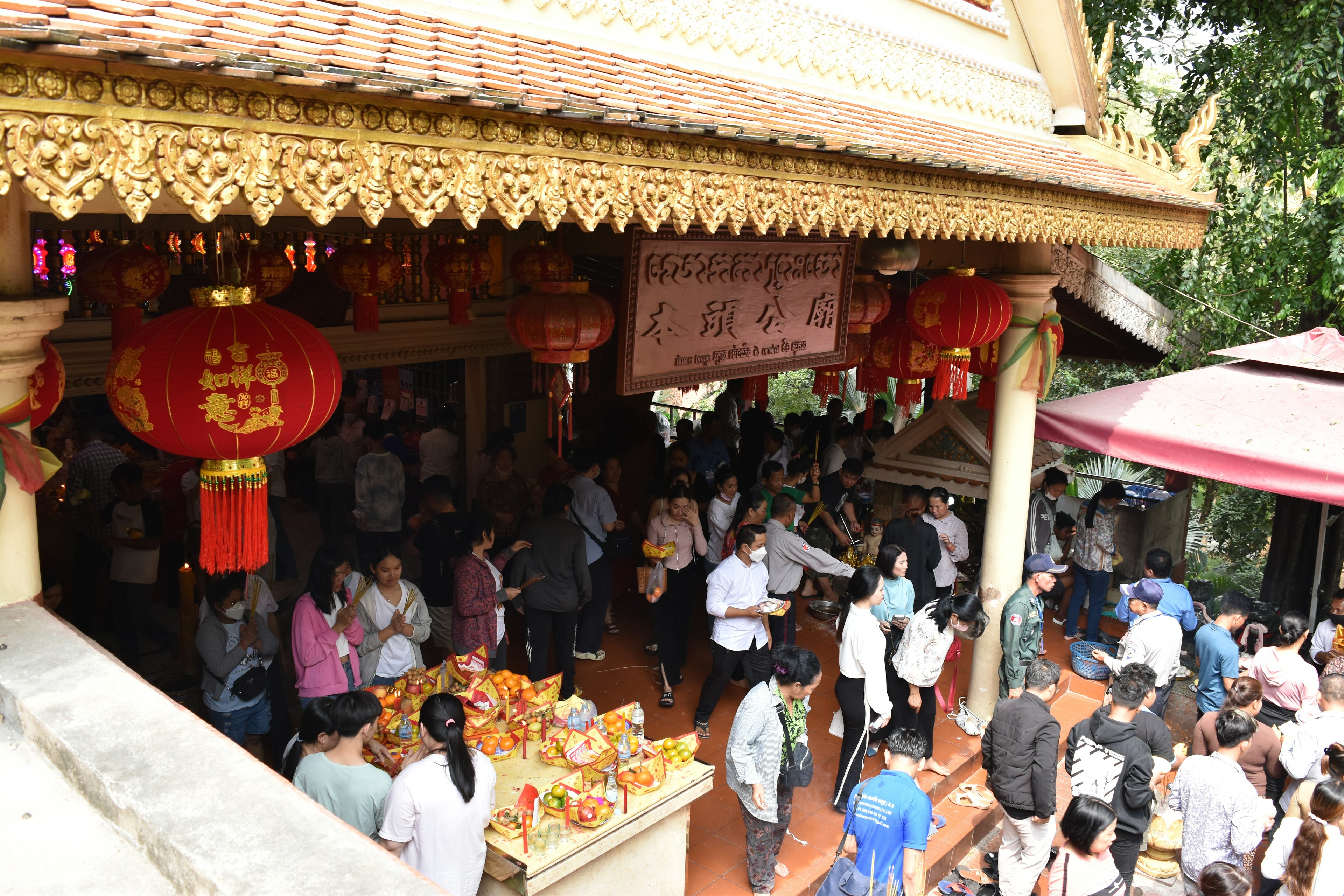 Busy temple exterior with colorful lanterns and crowds of people