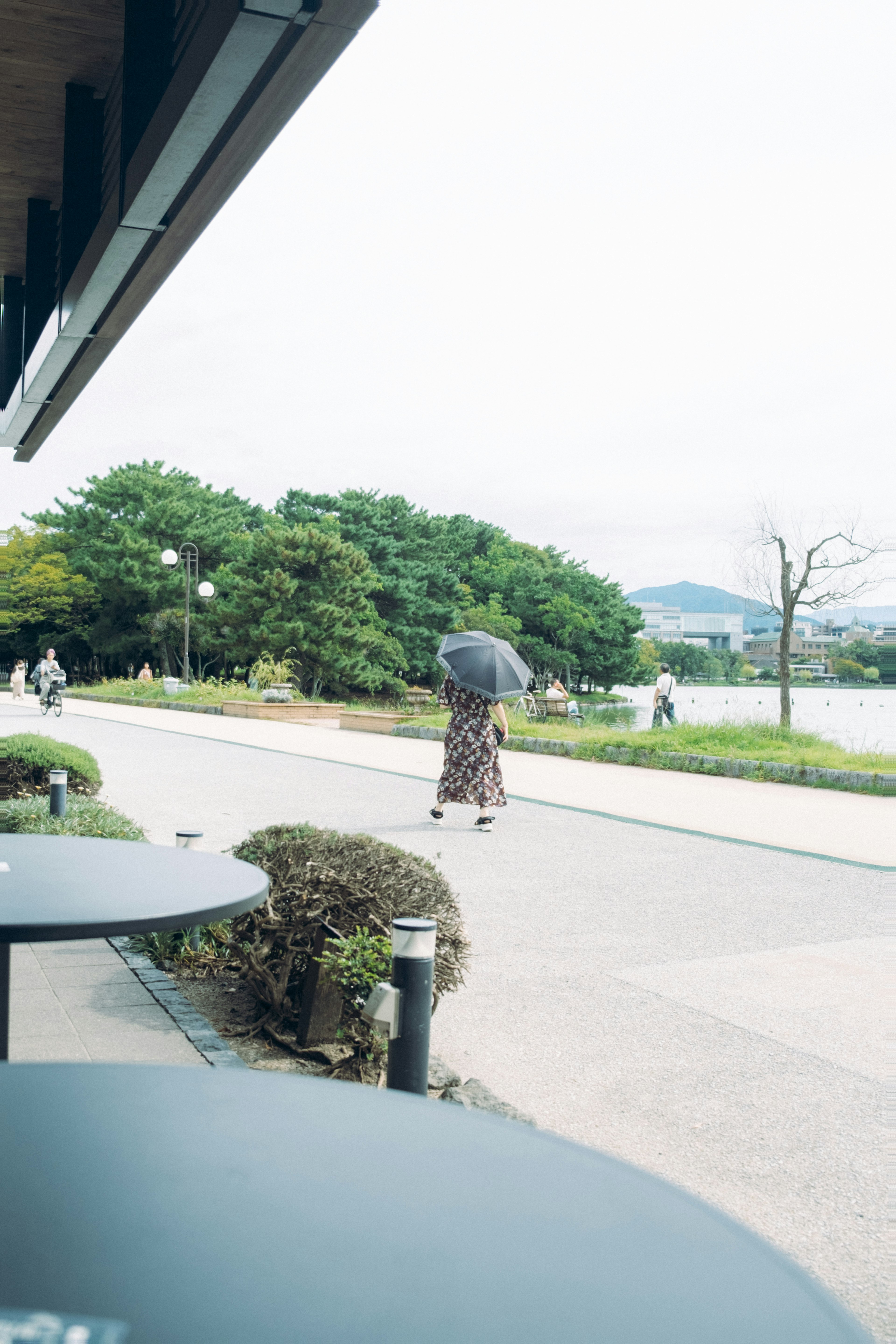 静かな公園の散歩道に傘を持った人が歩いている