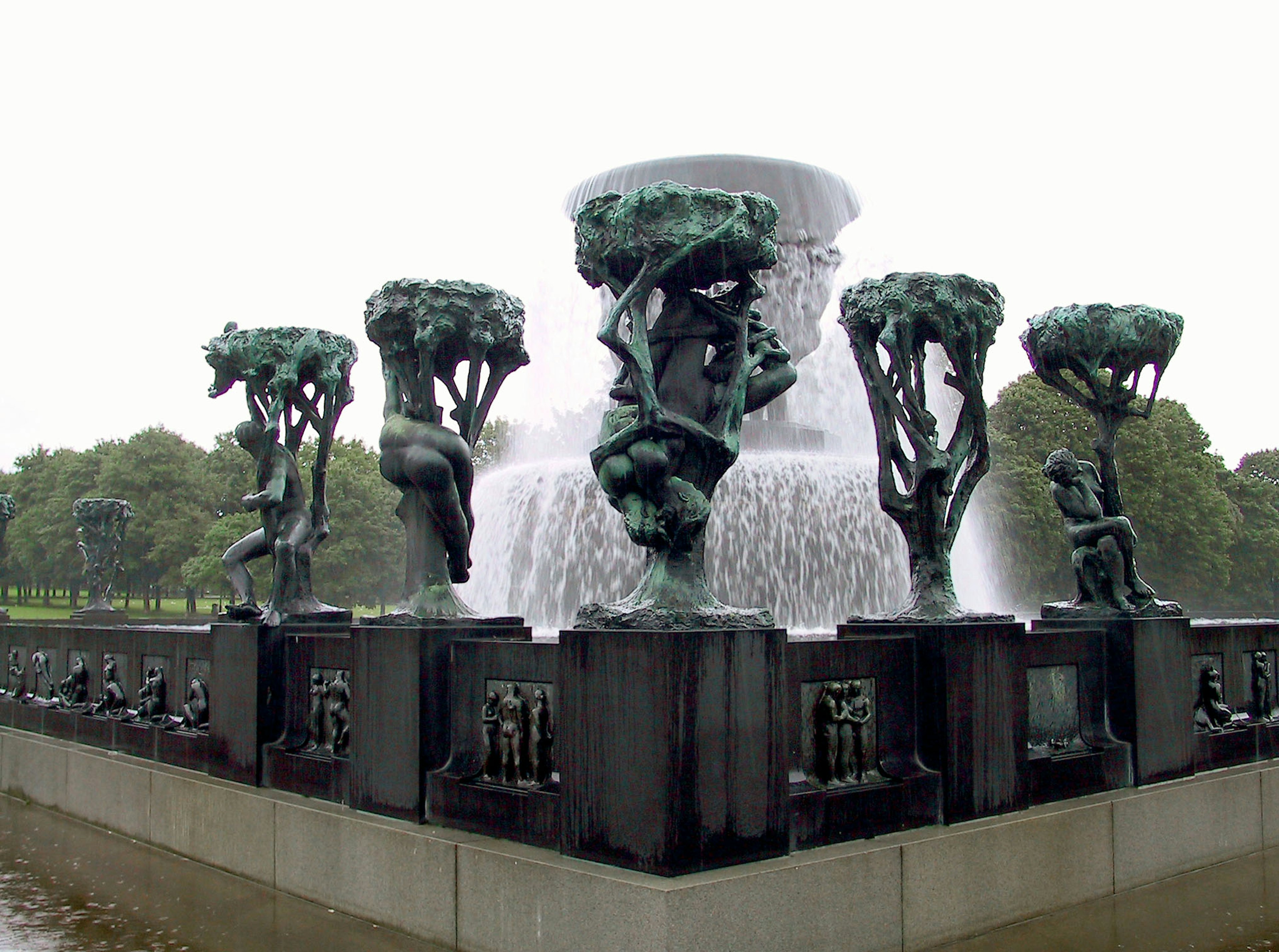 Brunnen mit Skulpturen in einem Park mit grünen Baumskulpturen