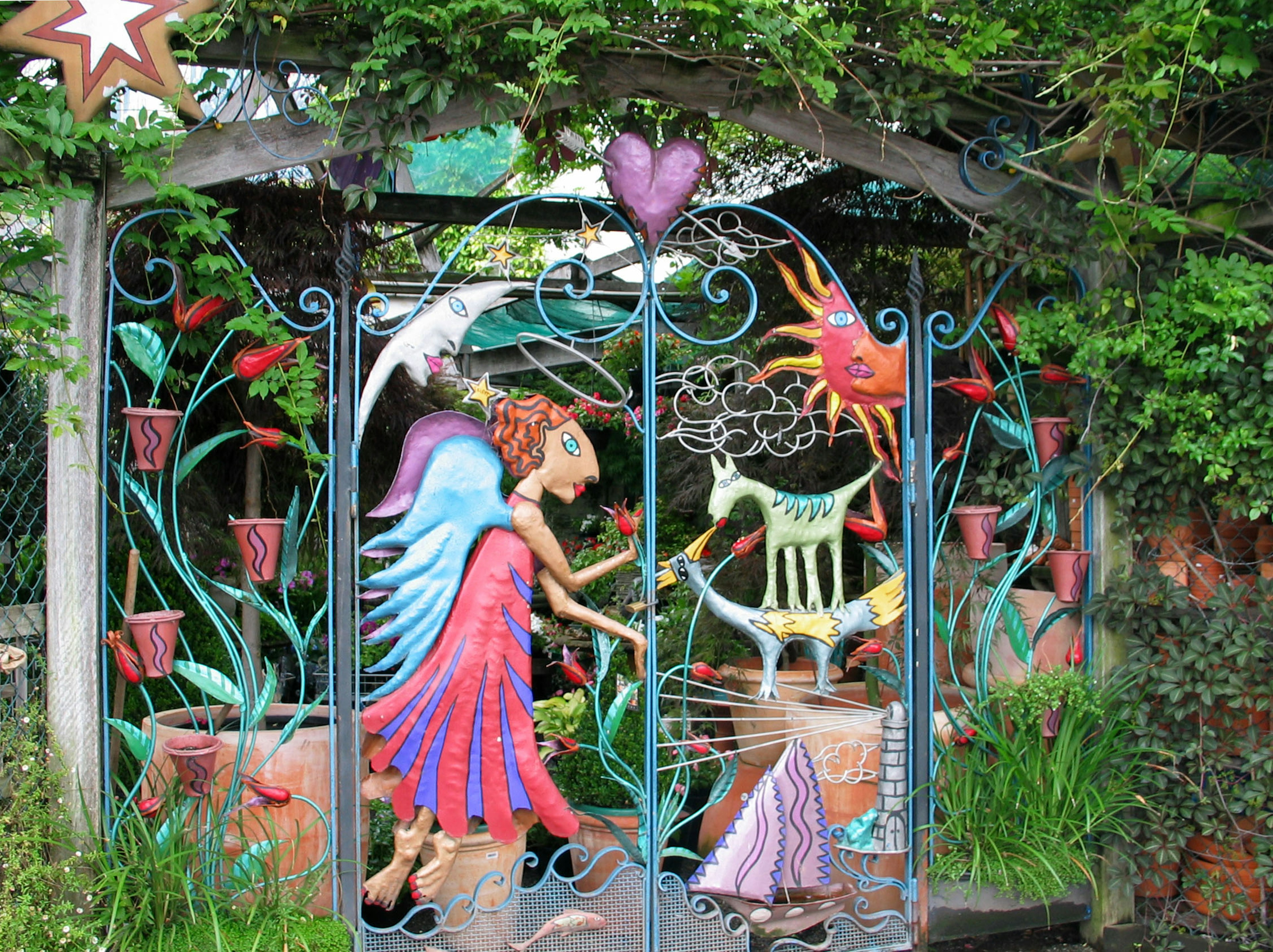 Colorful gate featuring a fairy and plant designs in a garden entrance