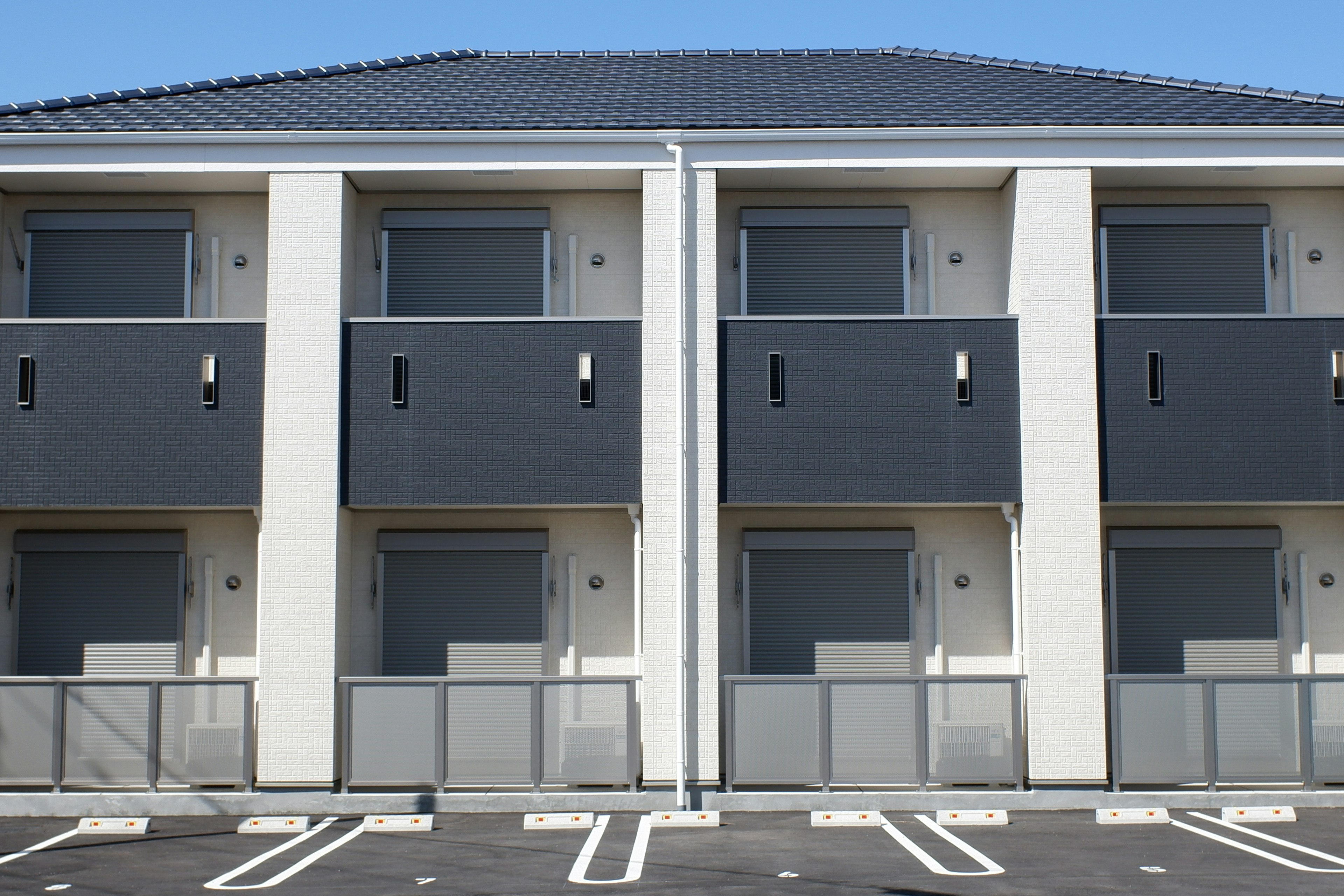 Façade d'appartement moderne à deux étages avec un design élégant sous un ciel bleu clair