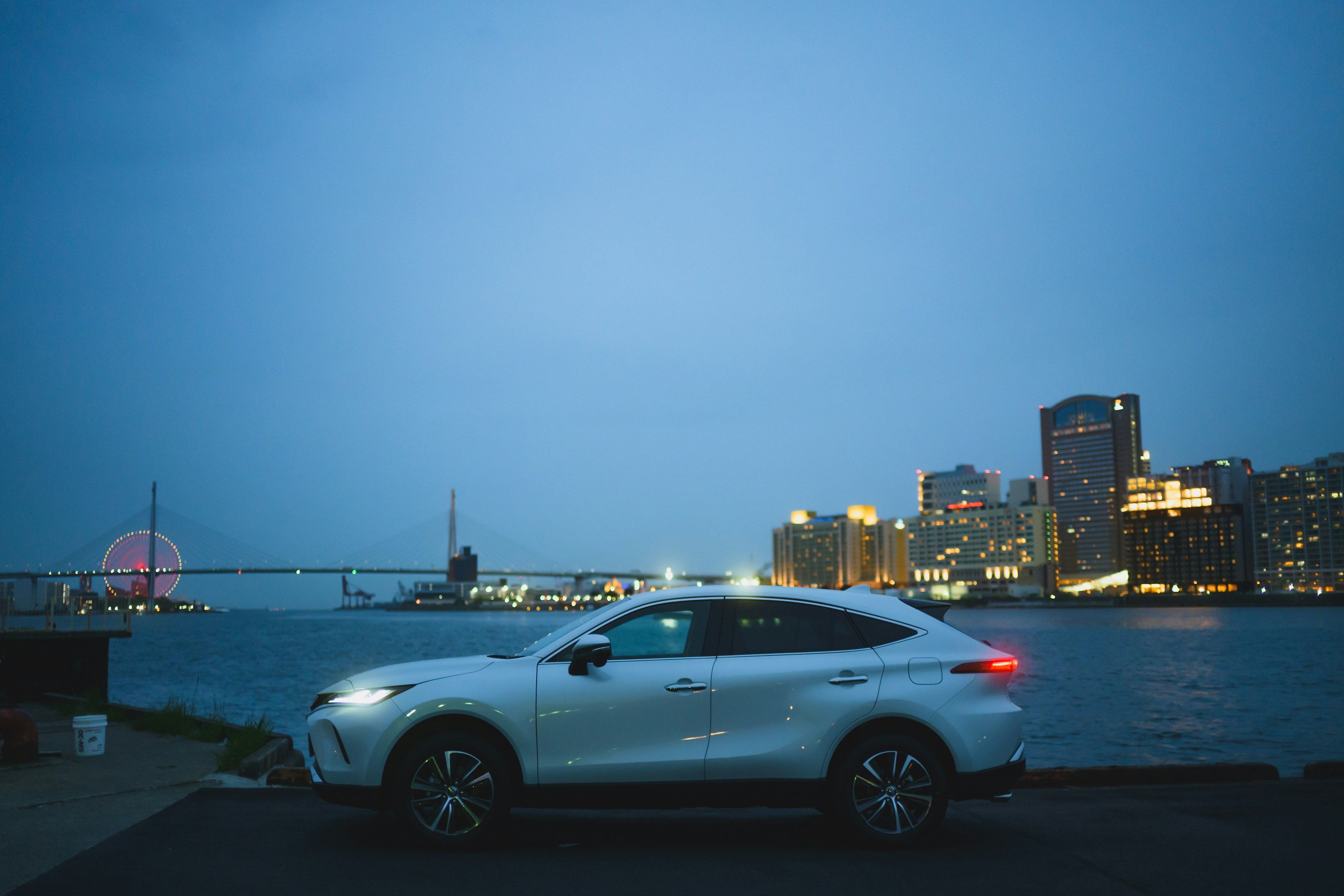 SUV bianco parcheggiato sul lungomare con skyline della città di notte