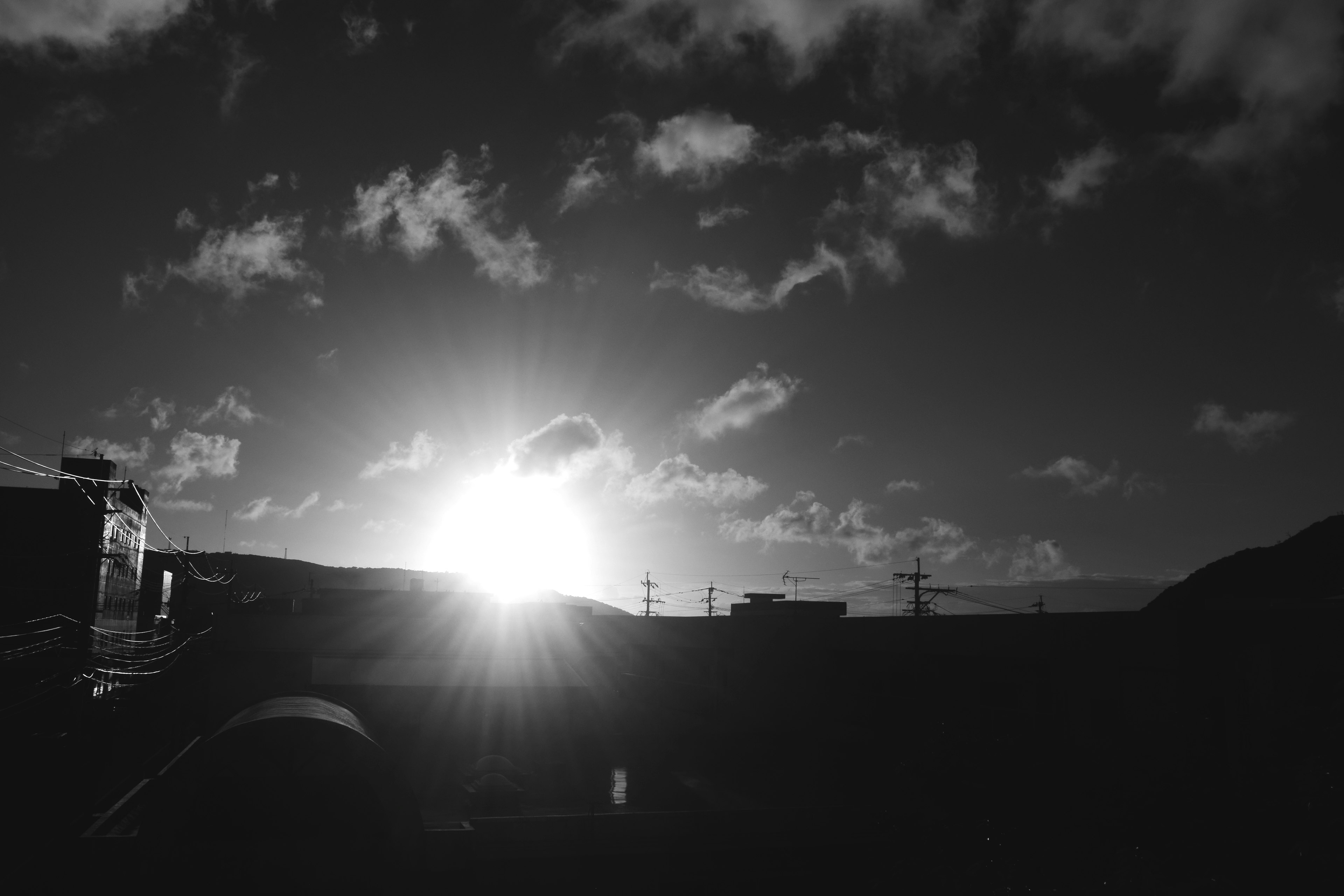 Paisaje en blanco y negro con un atardecer brillante y siluetas de nubes