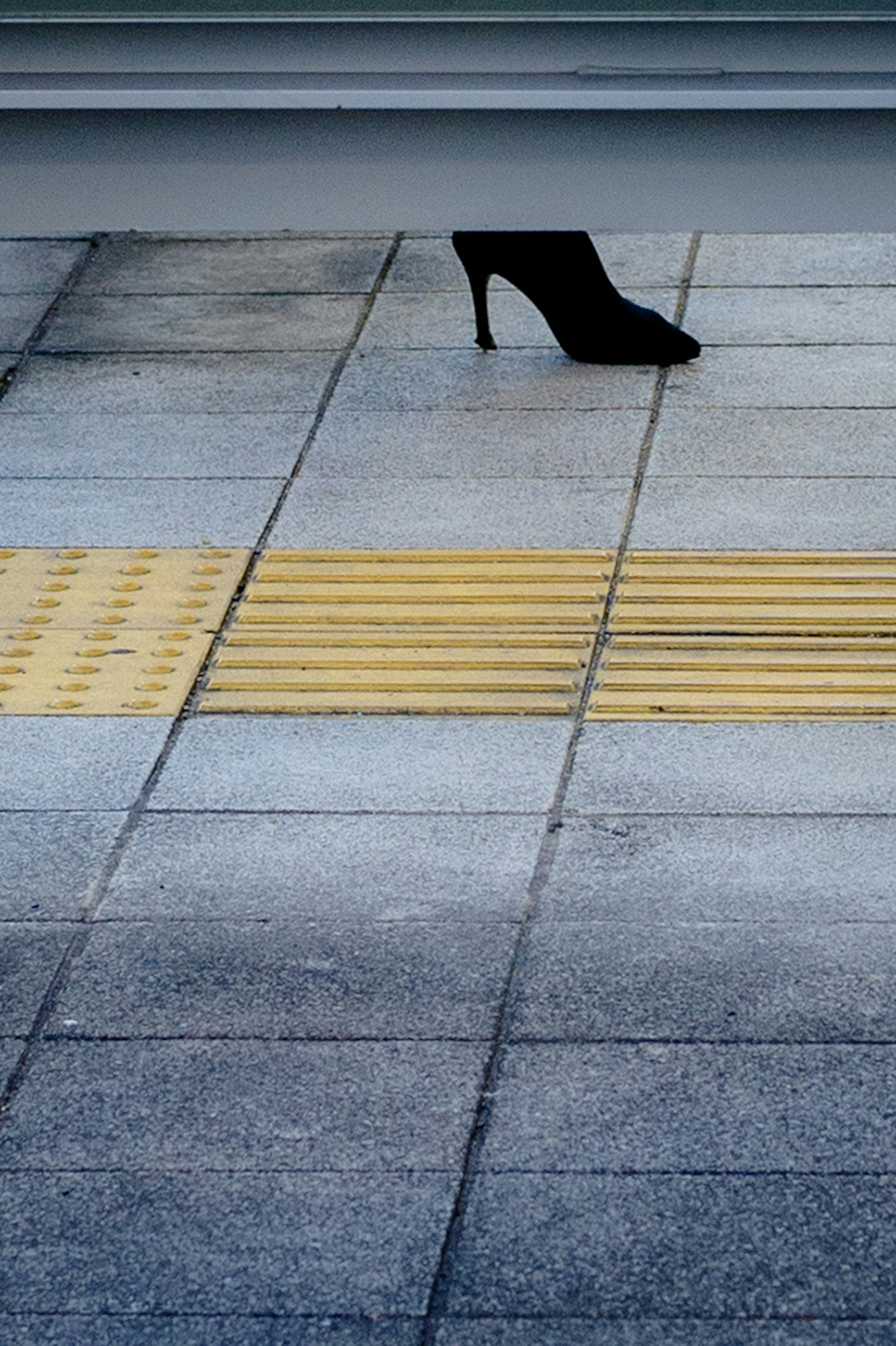 Una scarpa nera con tacco posata a terra su una linea guida gialla