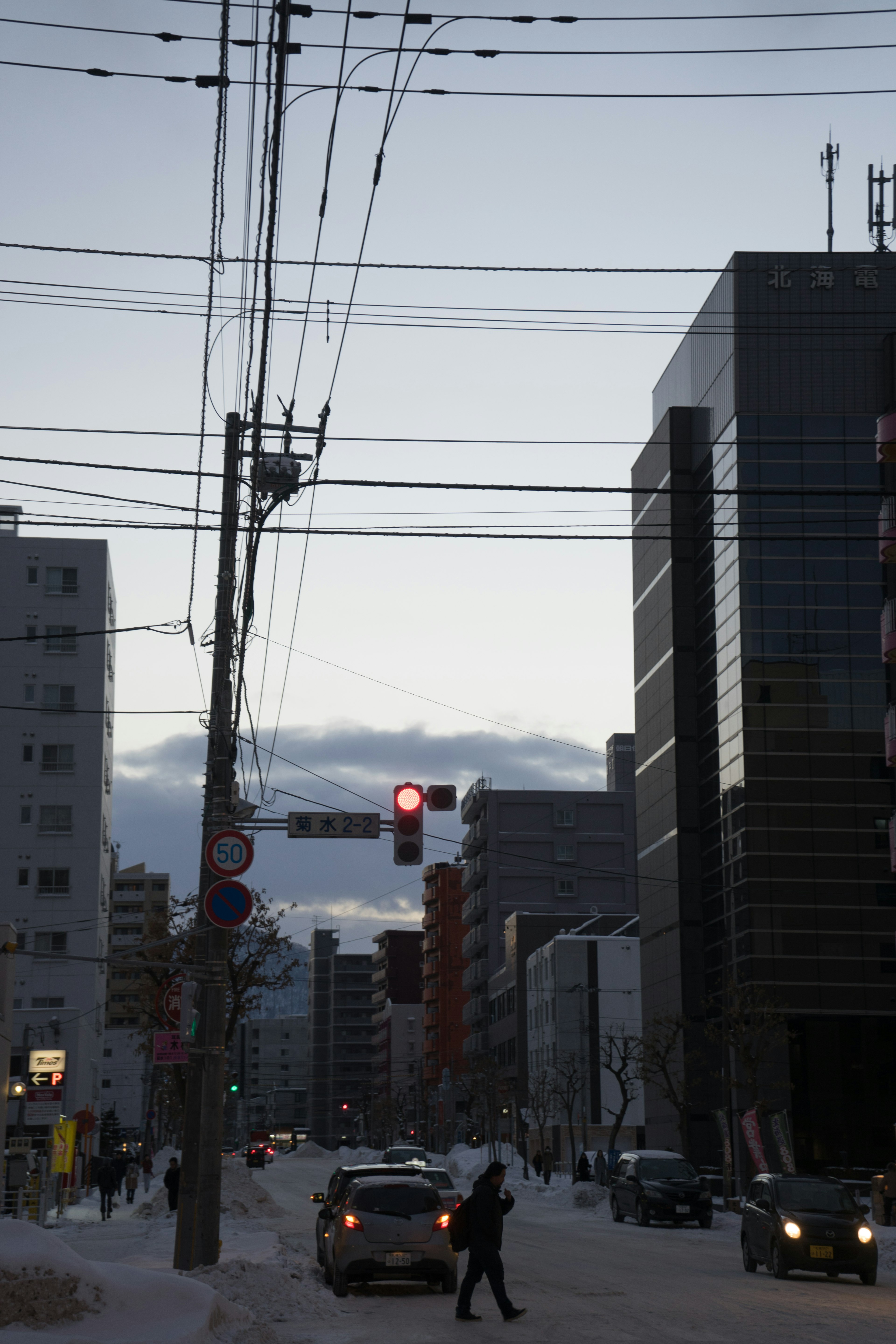 Una persona cruzando una calle urbana nevada con un semáforo rojo