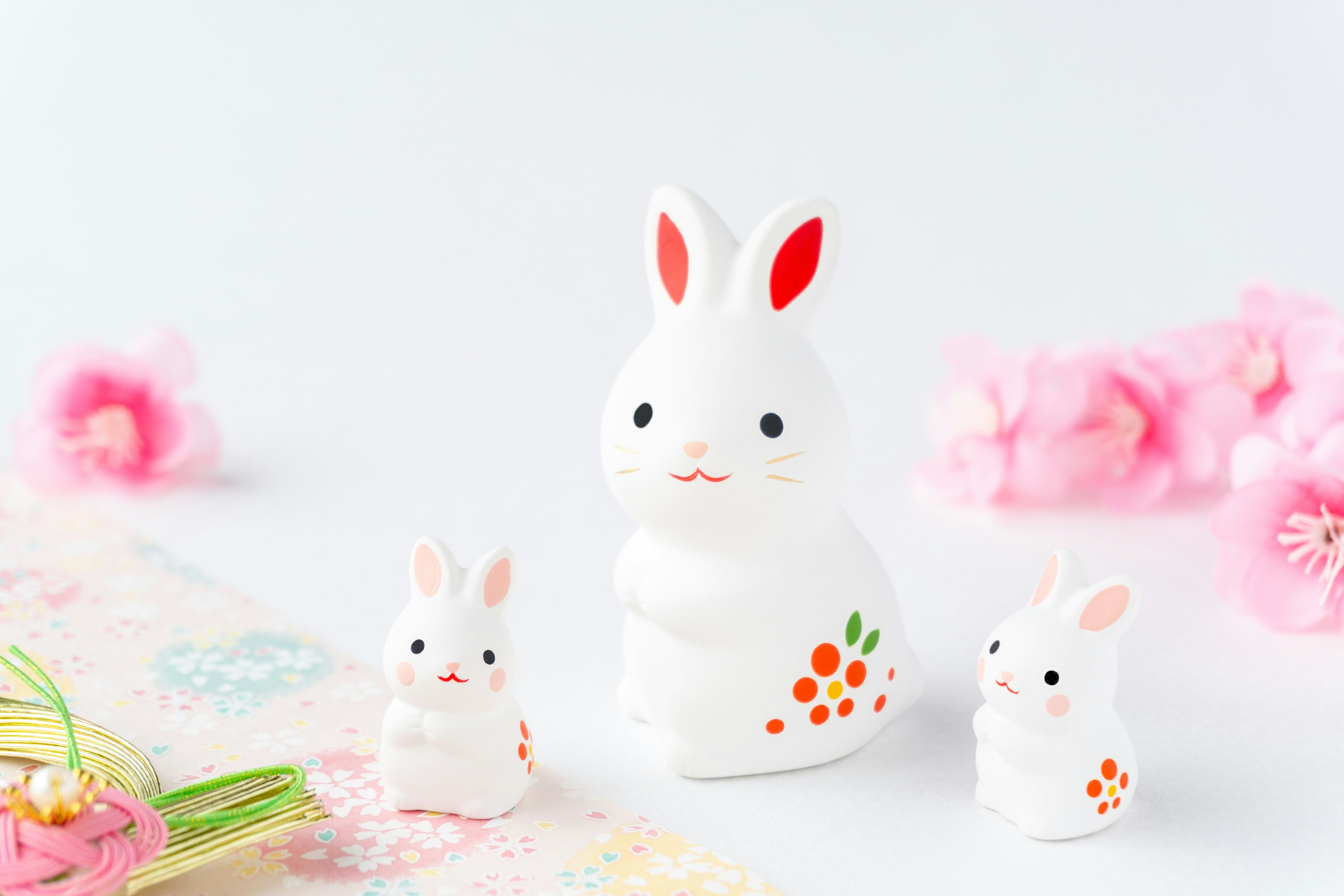 Trois figurines de lapin blanches avec des accents rouges disposées ensemble