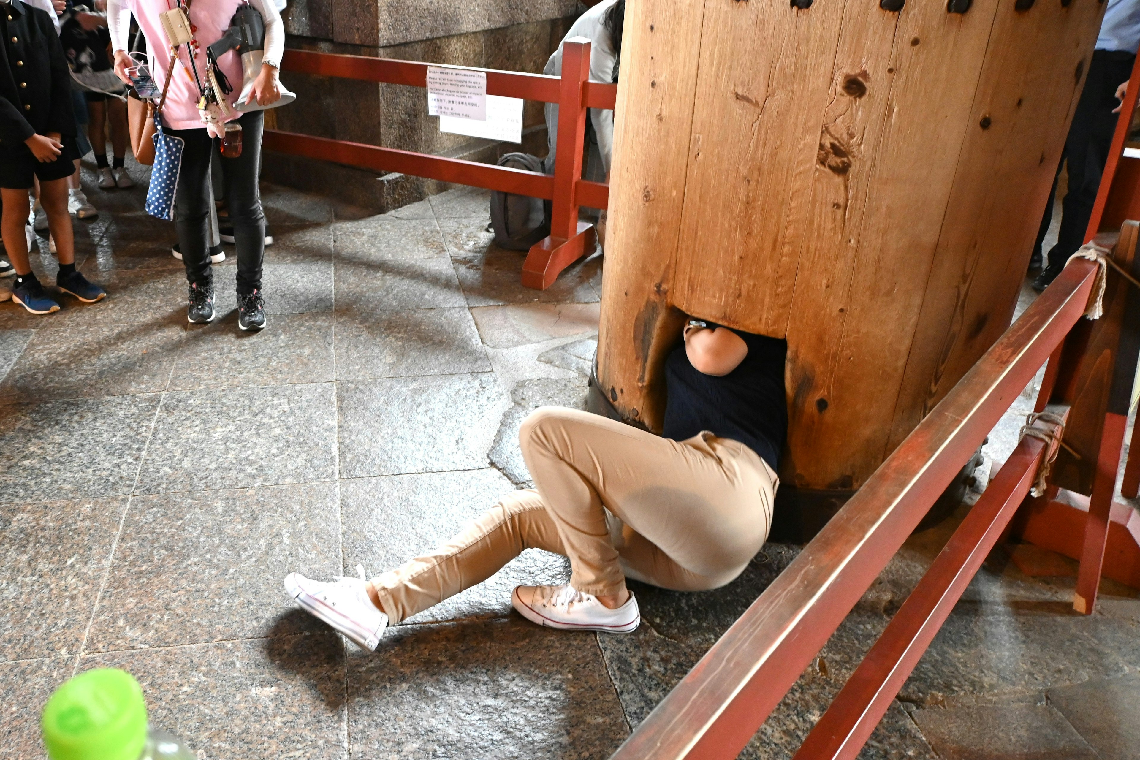 Una persona tratando de arrastrarse a través de un gran agujero en un pilar de madera