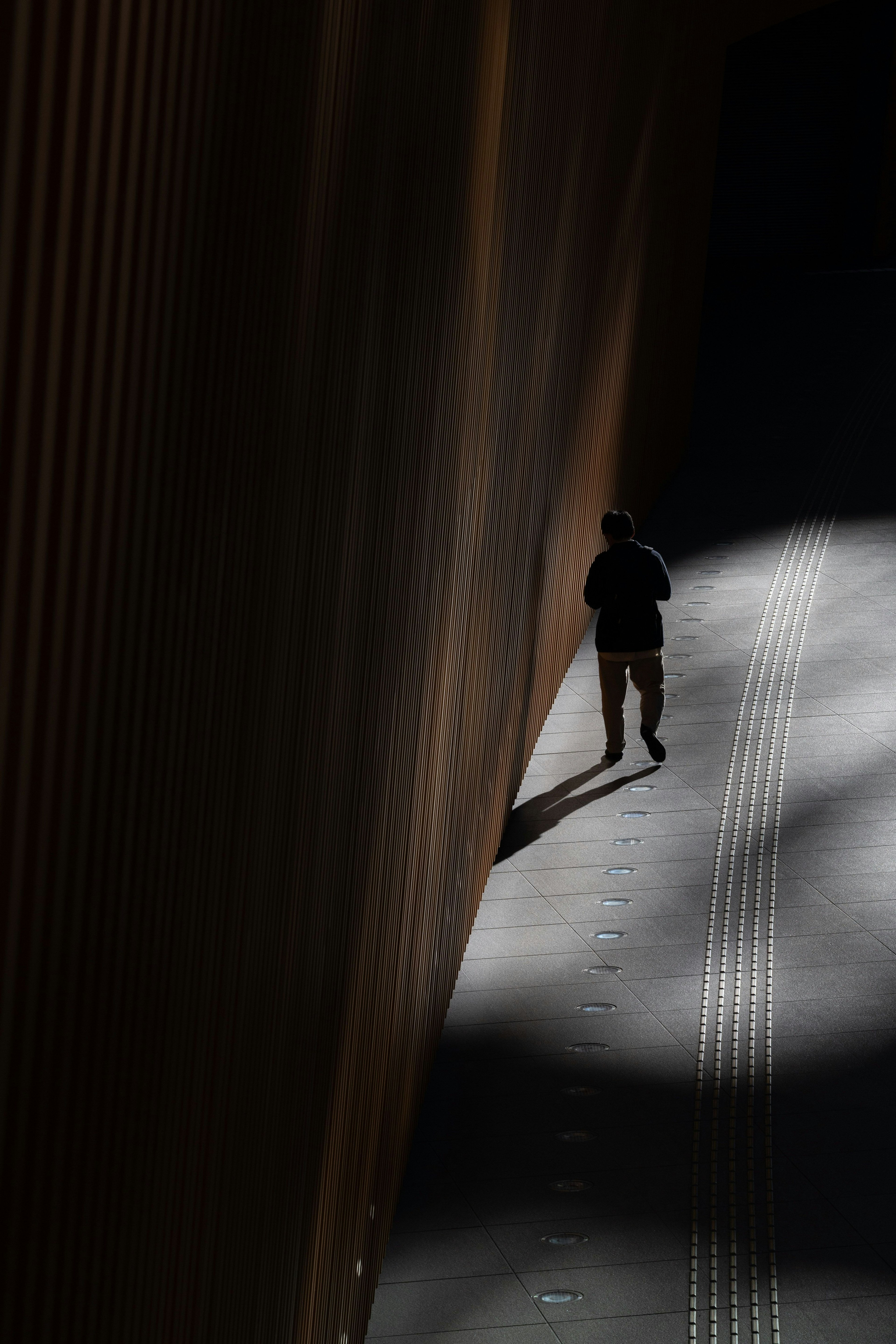 Silueta de una persona caminando en un pasillo oscuro con contraste de luz