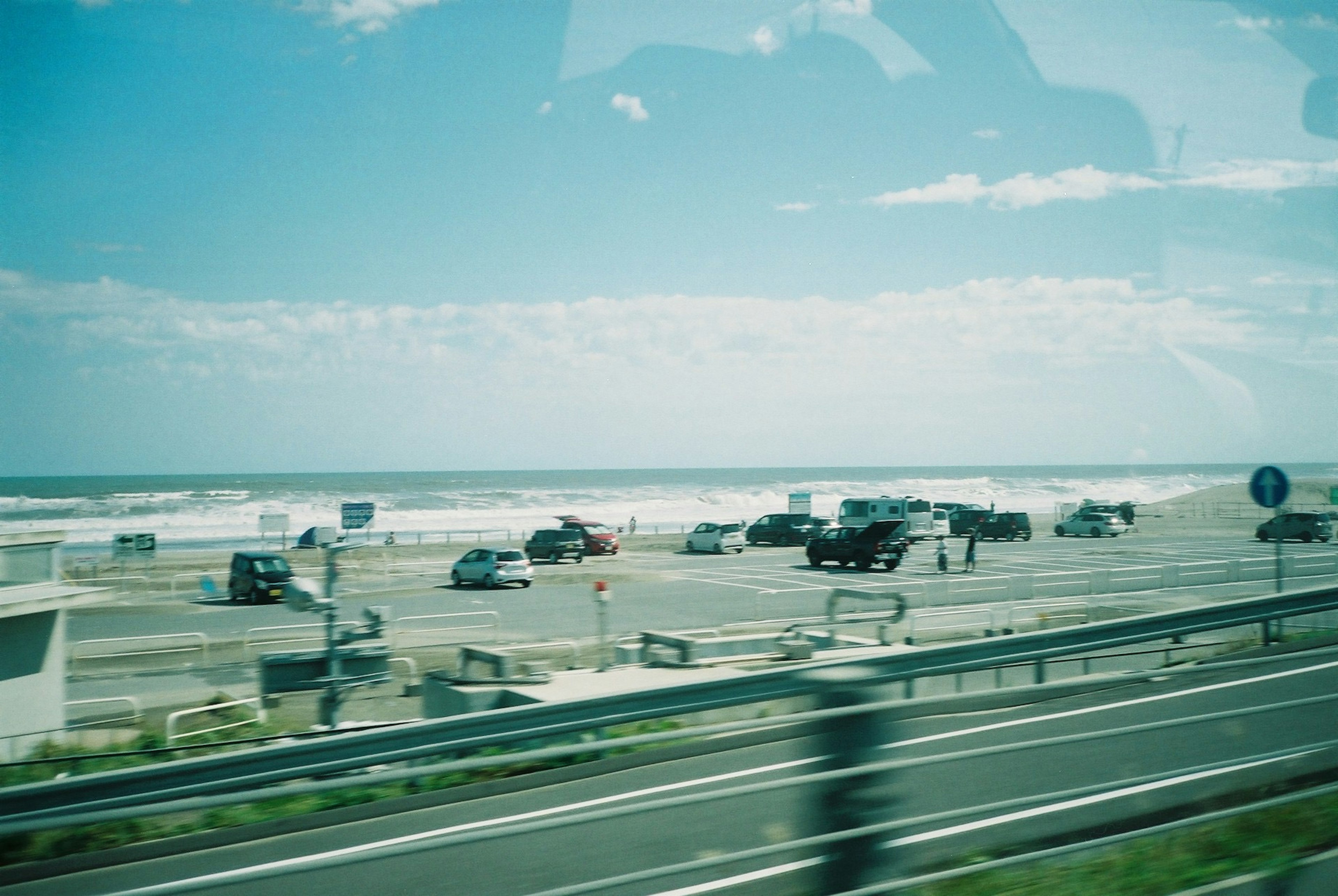 海の近くの駐車場に車が並ぶ風景