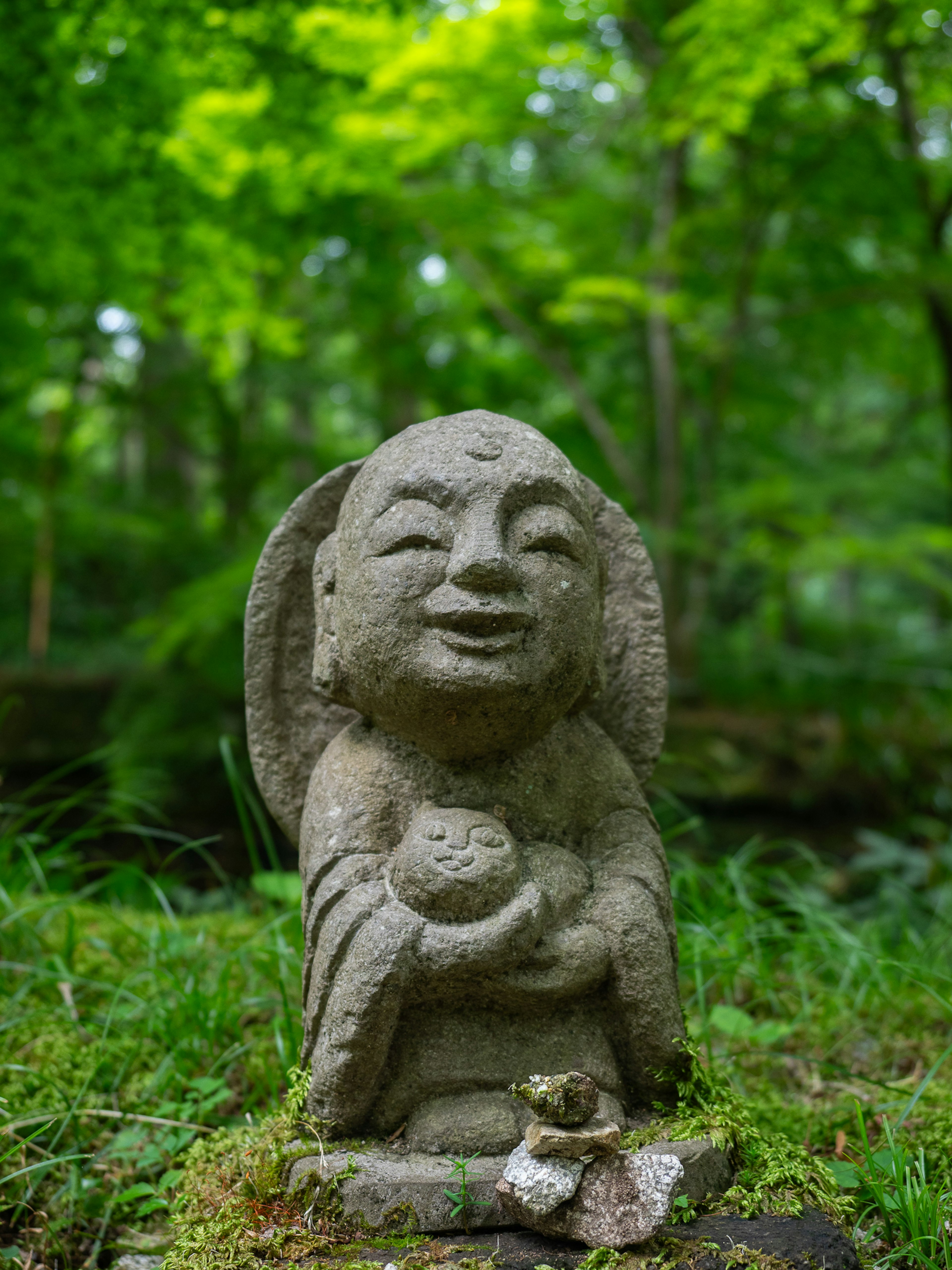 A smiling stone statue stands in a lush green forest